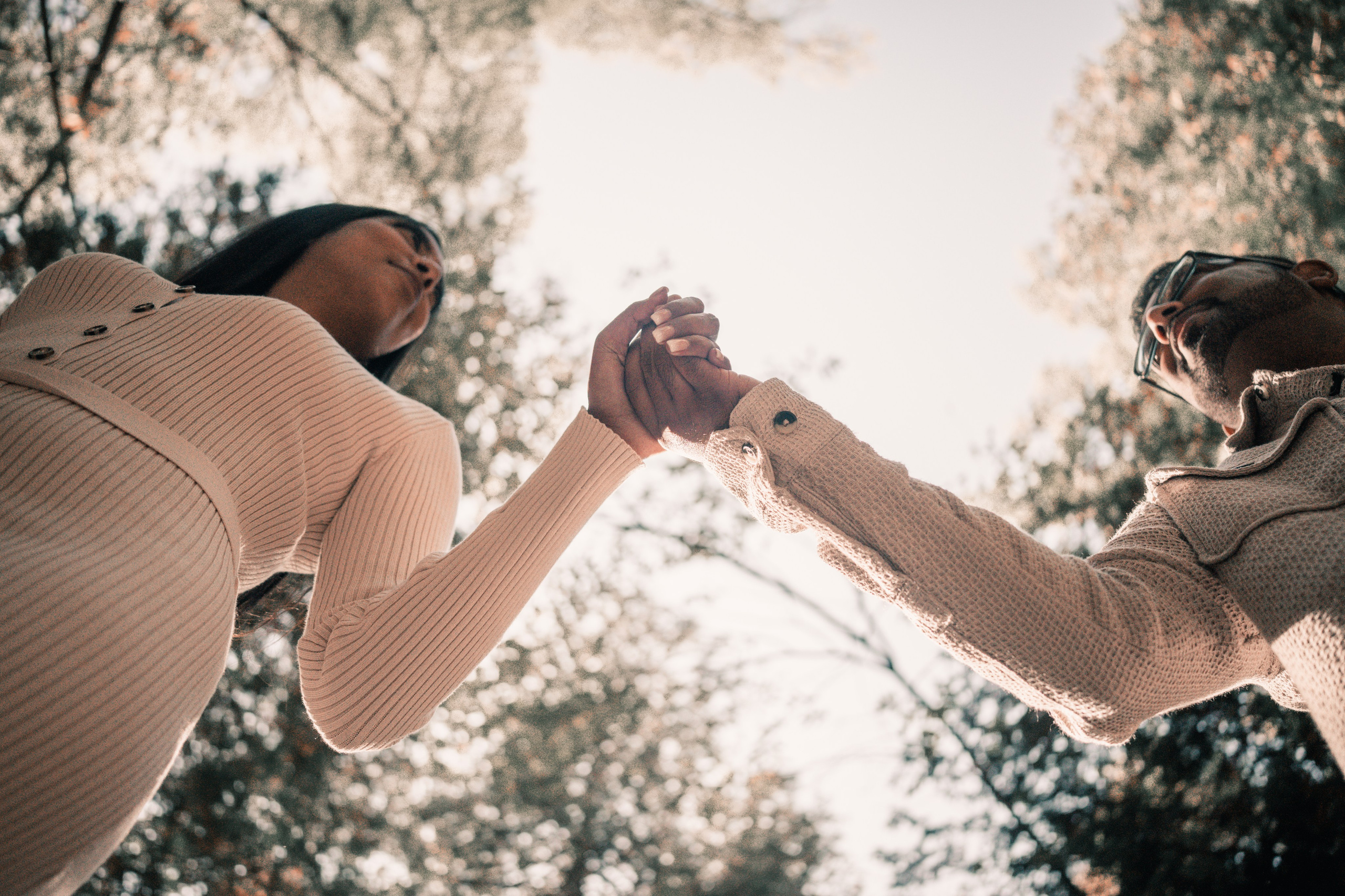 Couple holding hands while walking through a golden autumn park, capturing their pre-wedding moments