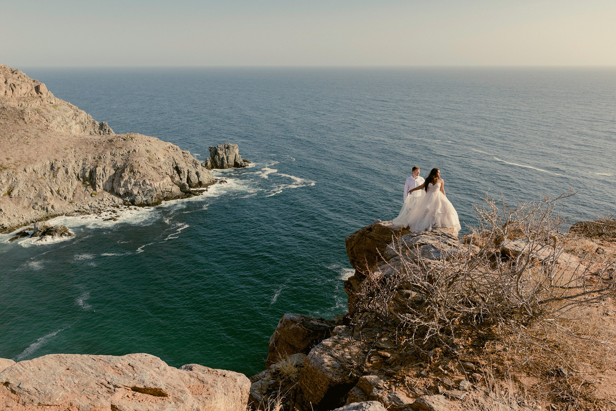 Trash the dress session at Punta Lobos, Todos Santos — couple on cliff overlooking the Pacific Ocean in Baja California Sur