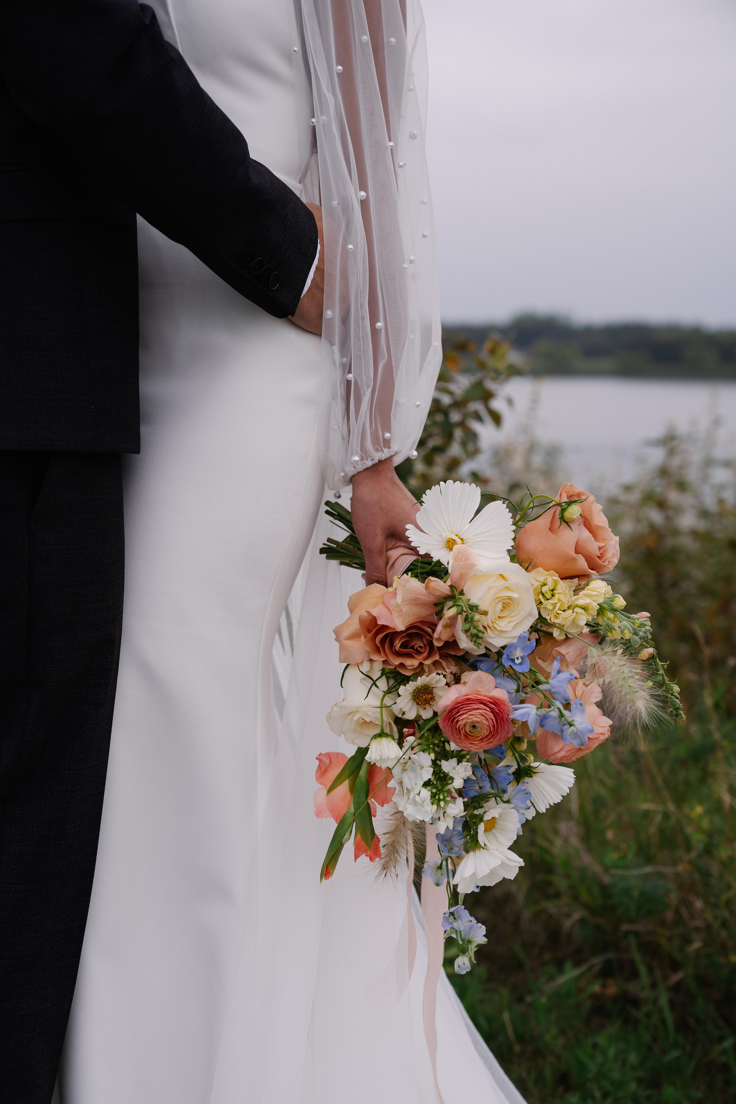 Groom embracing bride while she holds a bouquet.