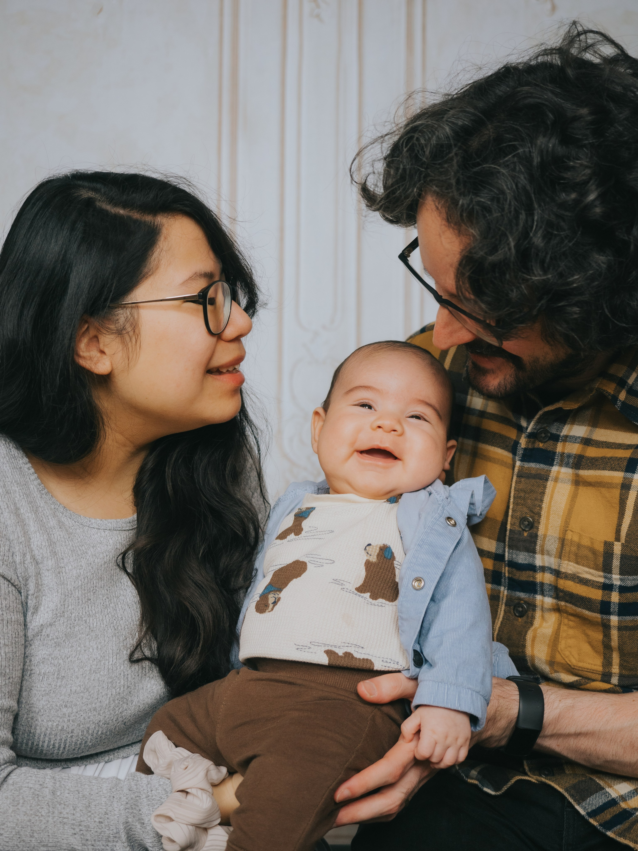 Infant smiling while parents are looking at him.