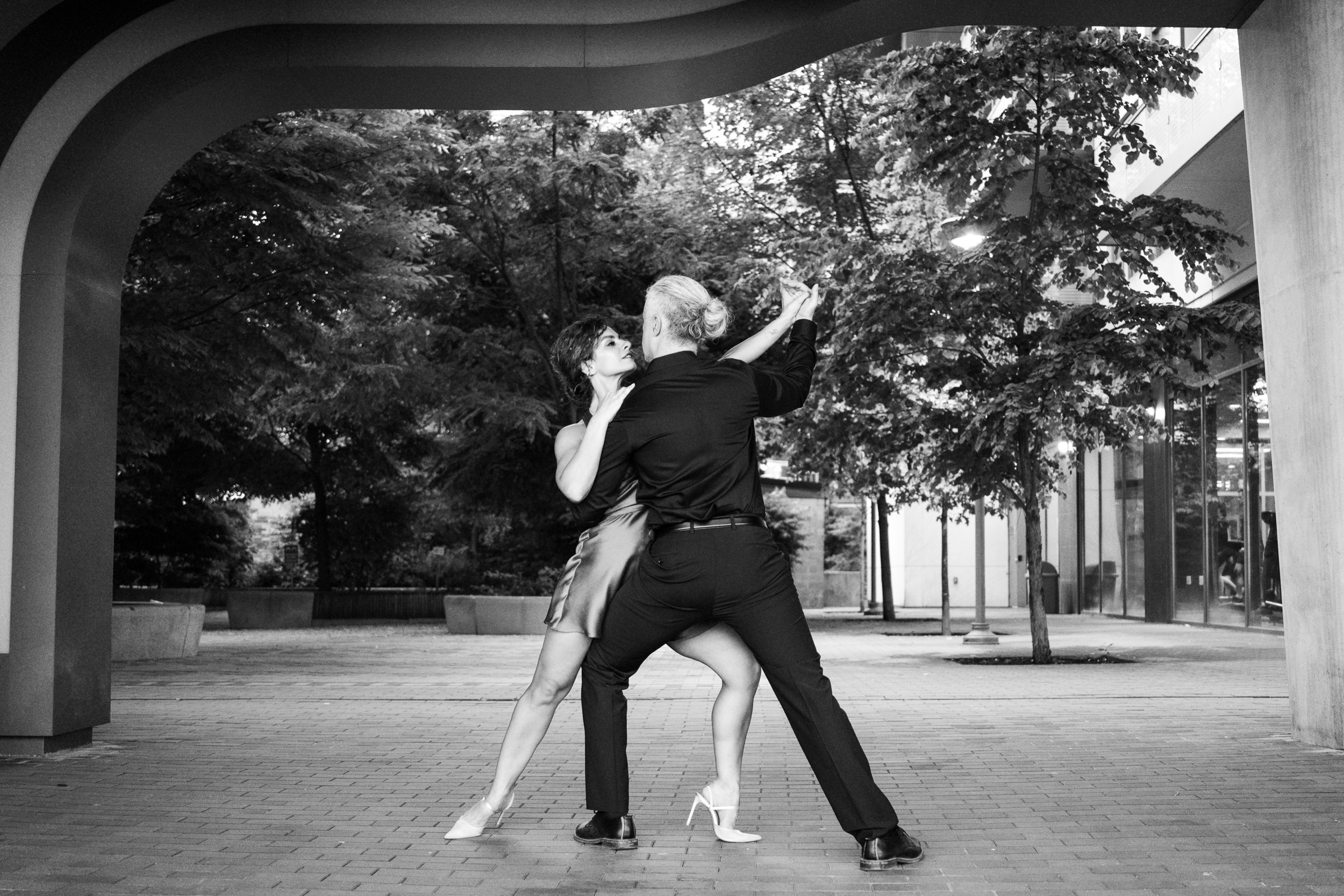 Couple dancing on a quiet street under string lights — celebrating their upcoming wedding