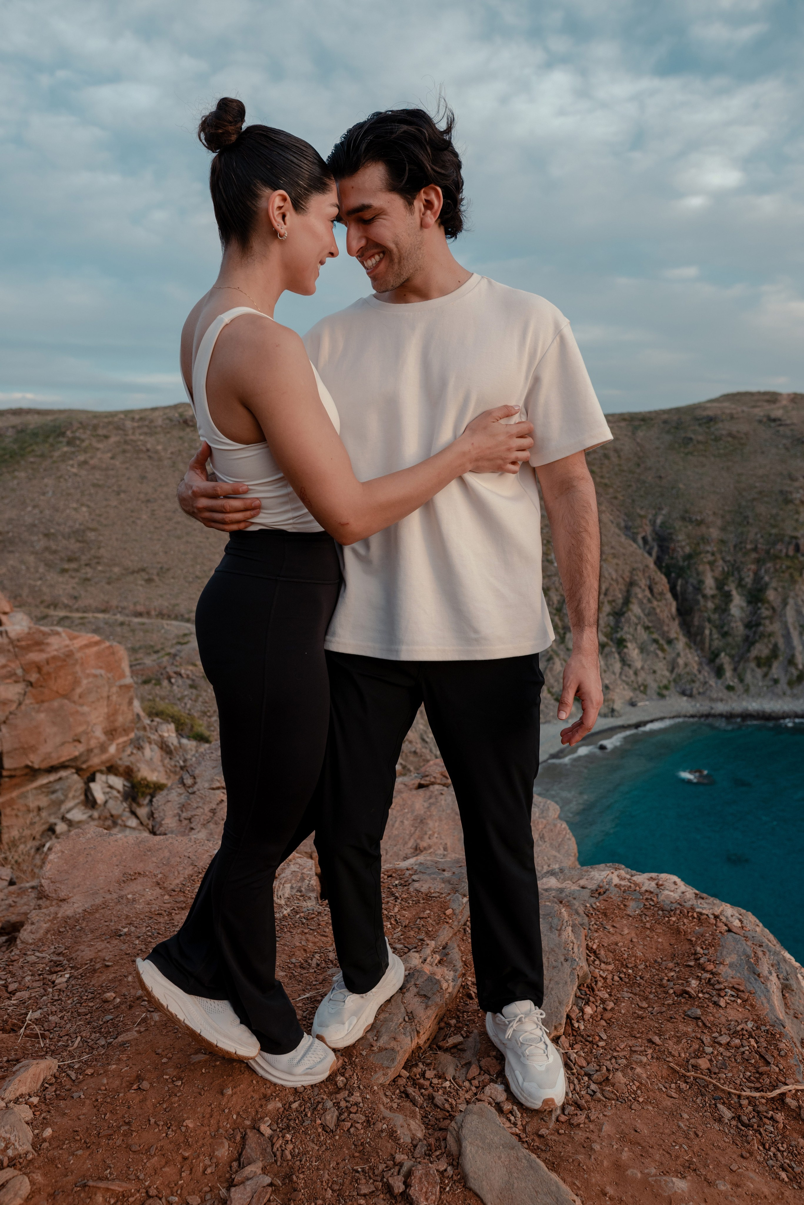 Intimate couple portrait at golden hour on Punta Lobos cliffs overlooking Pacific Ocean, Todos Santos