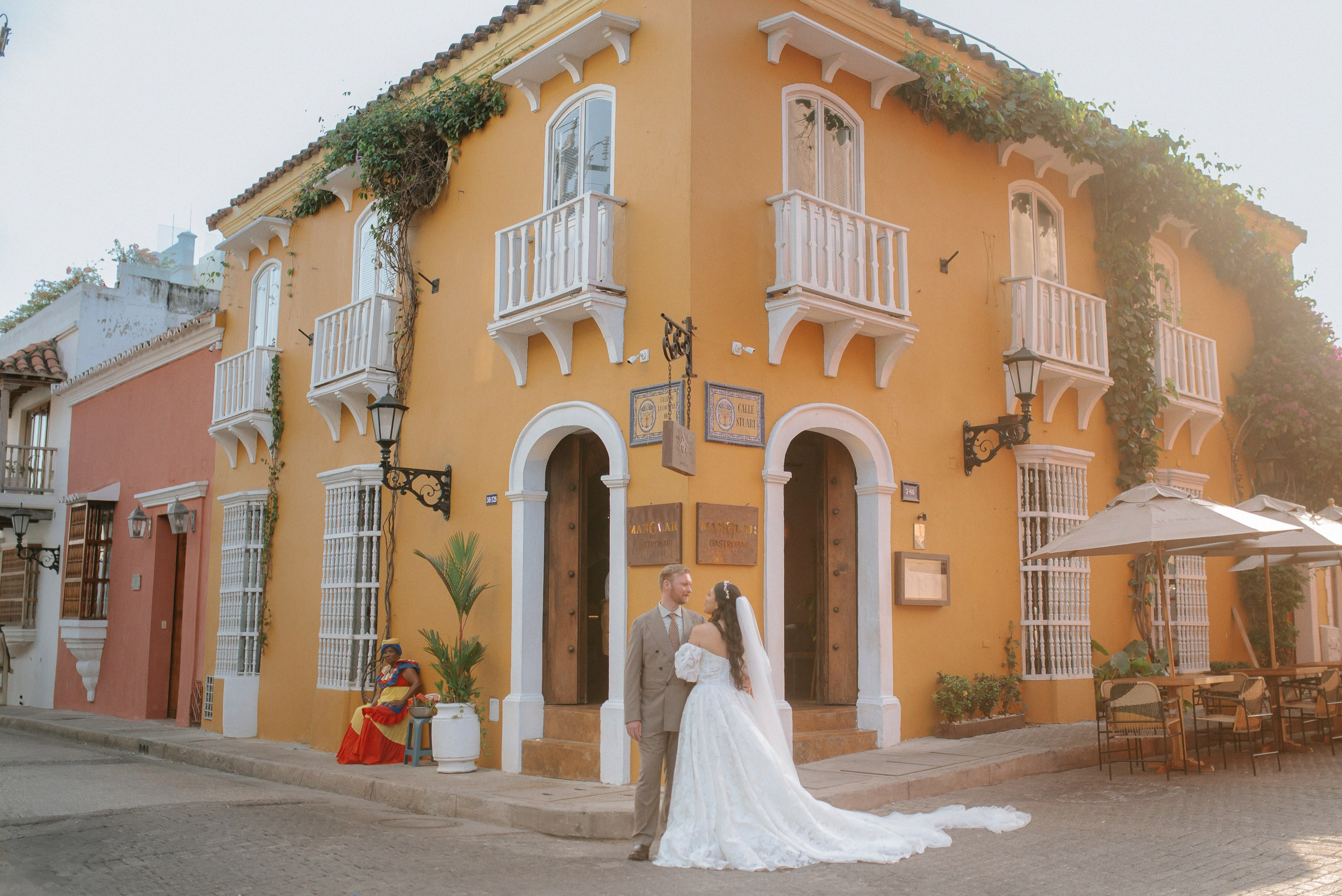 Bride and groom in front of a colorful colonial building in Cartagena, destination wedding photography