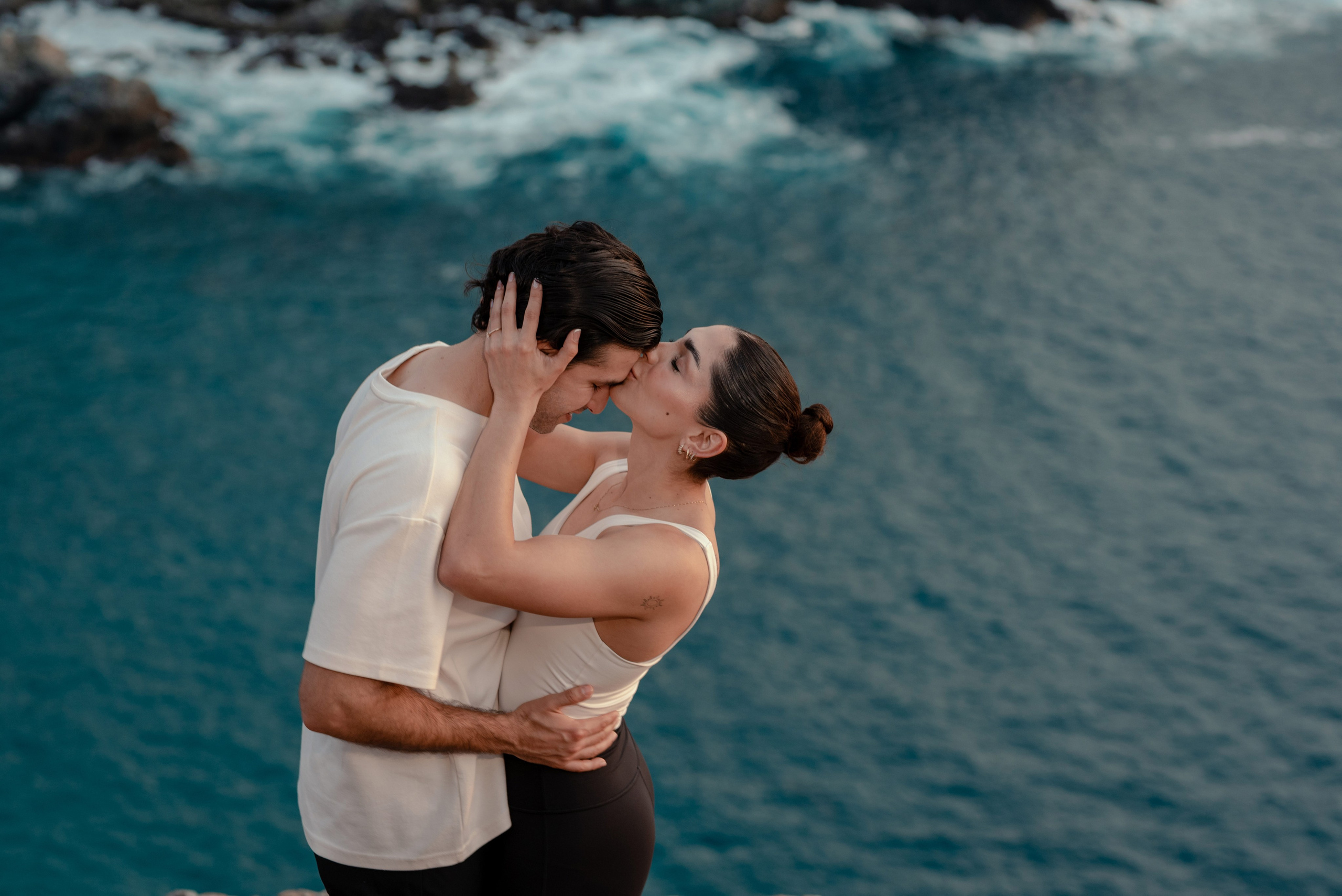 Couple kissing during engagement session at Punta Lobos with deep blue Pacific Ocean backdrop, Todos Santos Baja California Sur