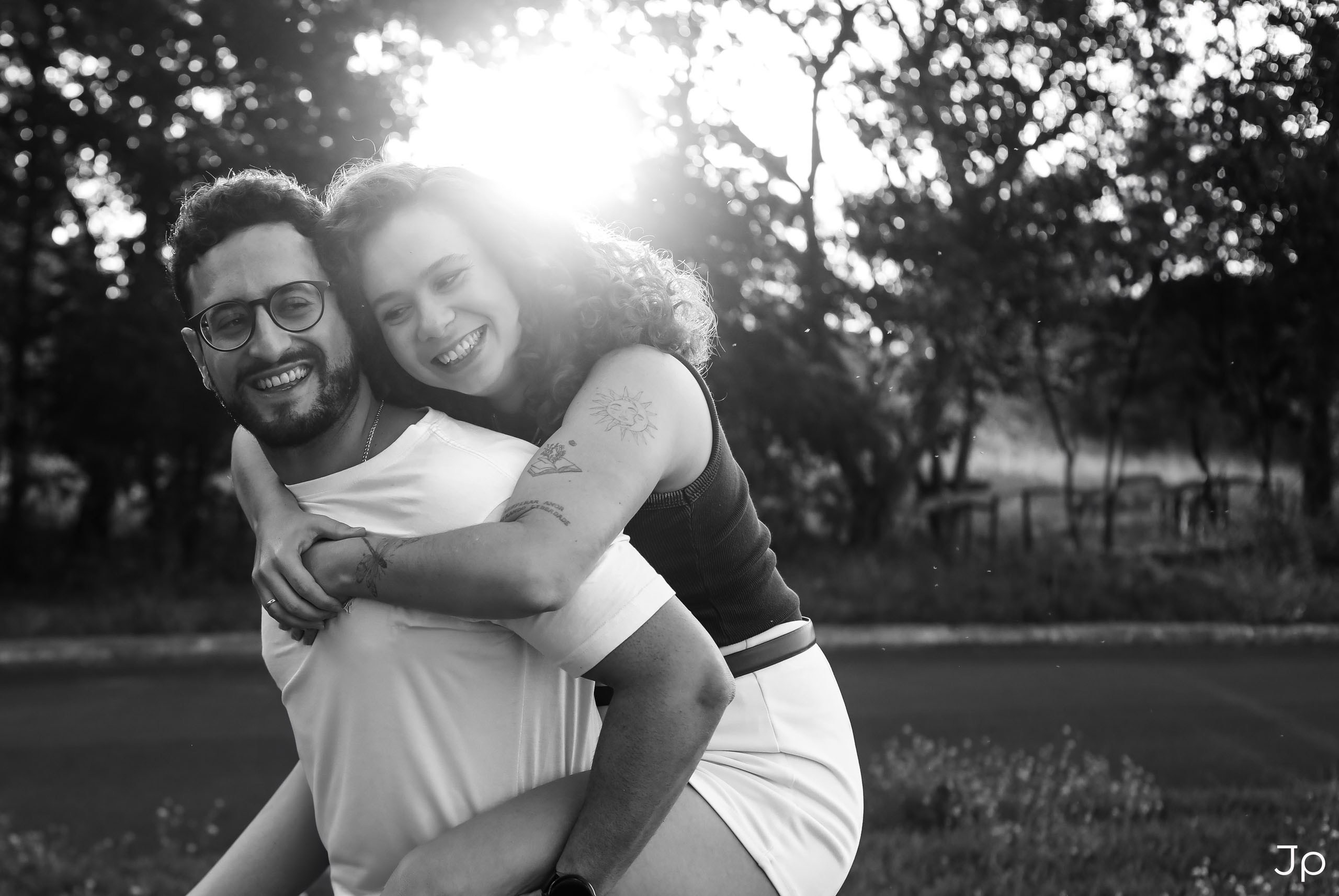 Foto em preto e branco do casal sorrindo juntos, com ela nas costas dele.