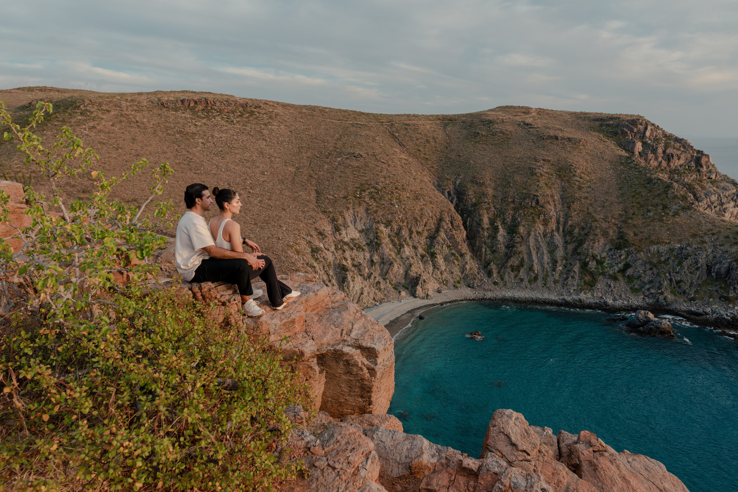 Couple portrait on rocky cliff edge overlooking the Pacific Ocean at Punta Lobos, Todos Santos Baja California Sur
