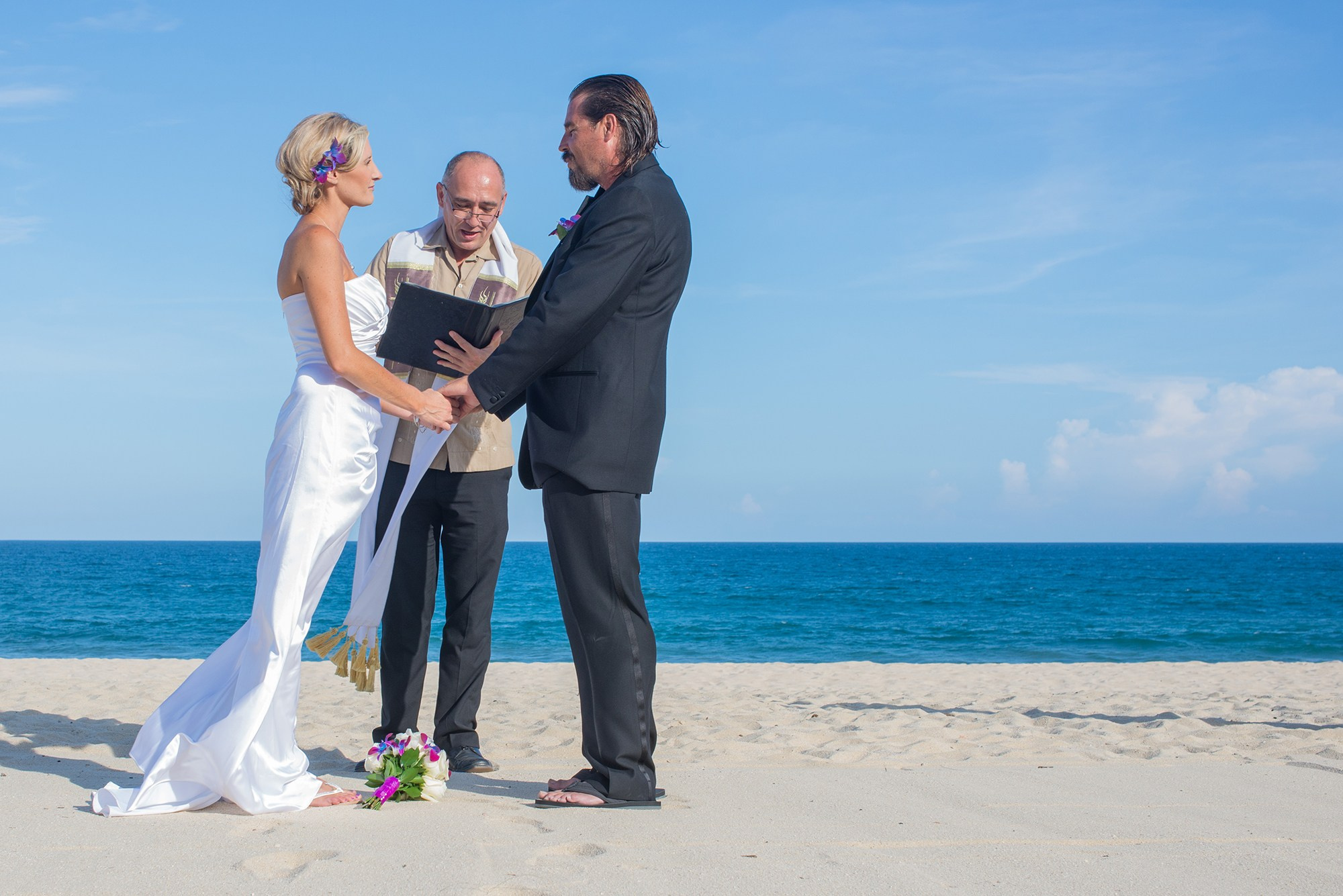 Couple standing with officiant during beach wedding ceremony in San José del Cabo