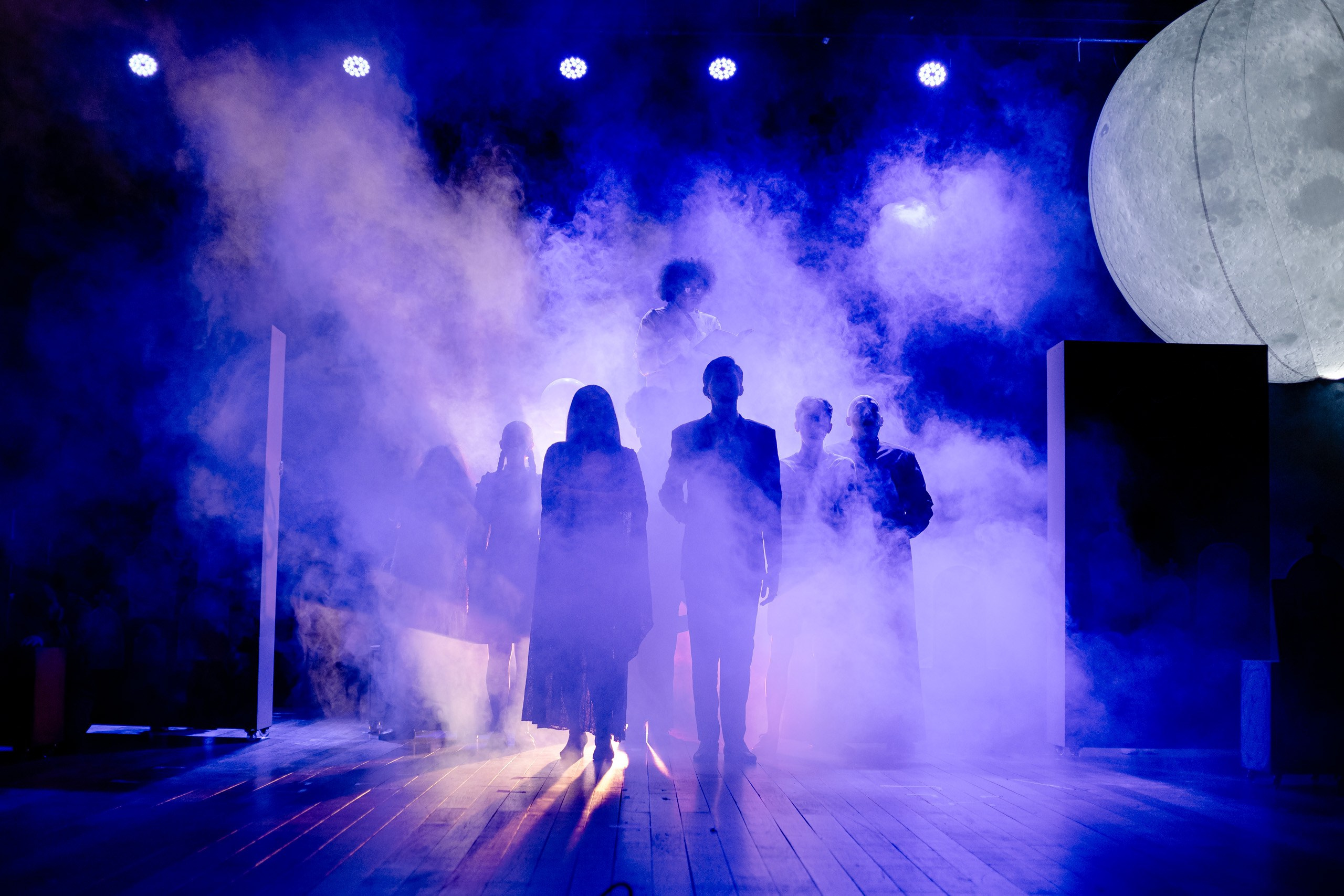 Apresentação teatral com grupo em silhueta.