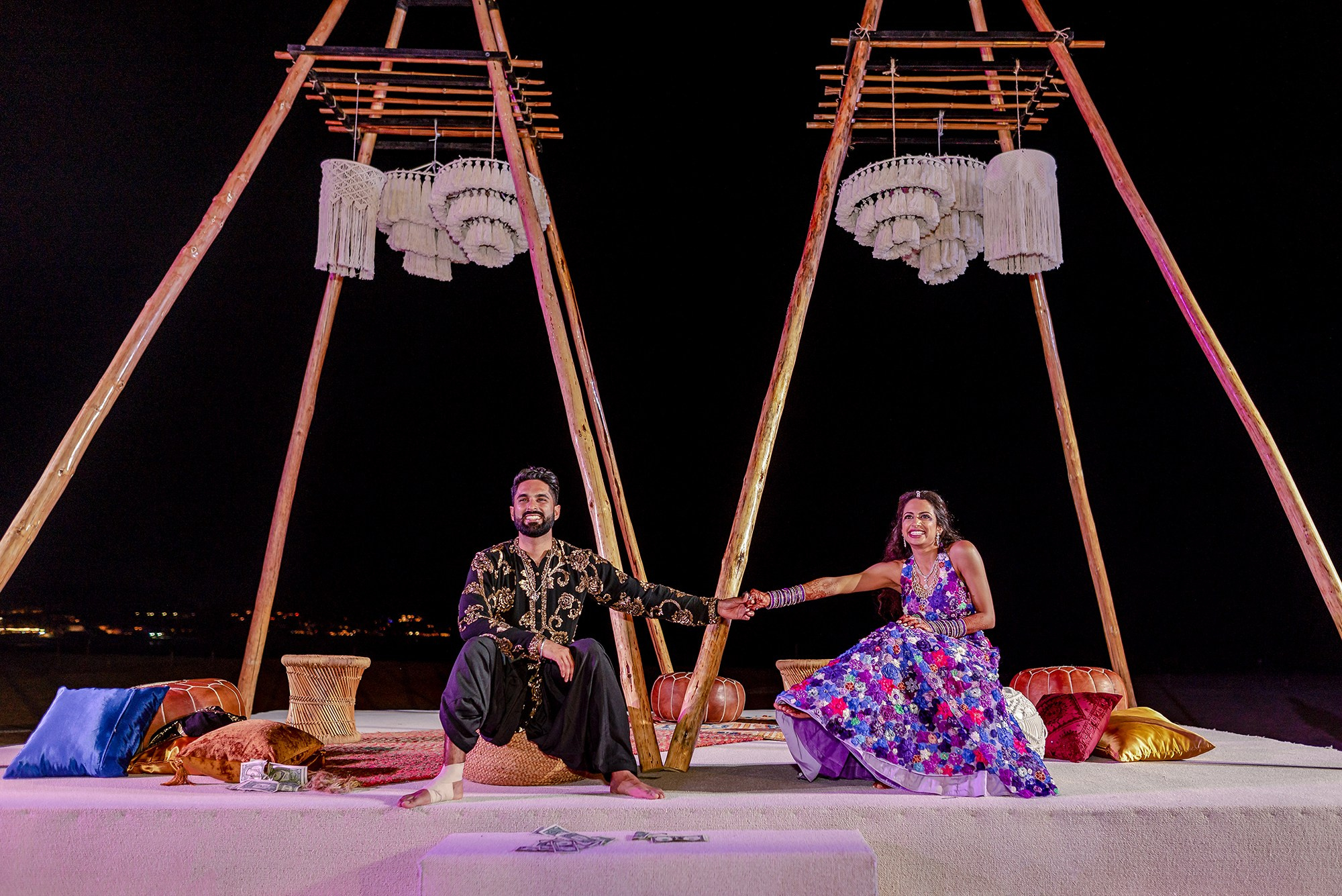 Couple holding hands under floral arch during multi-day Indian wedding at Paradisus Los Cabos