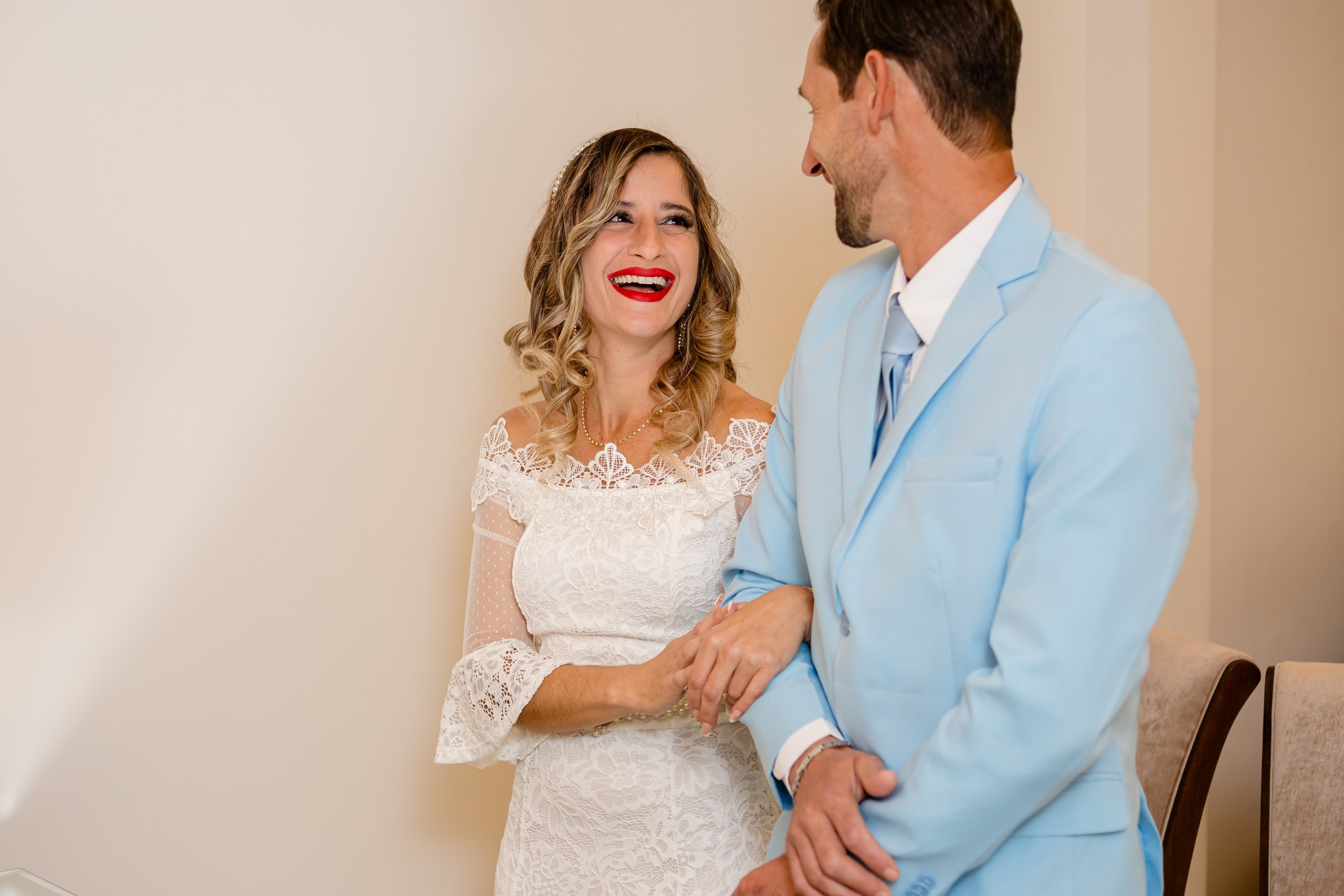 Fotógrafo de casamento civil em Navegantes; a noiva rindo radiante enquanto se apoia no braço do noivo durante a cerimônia.