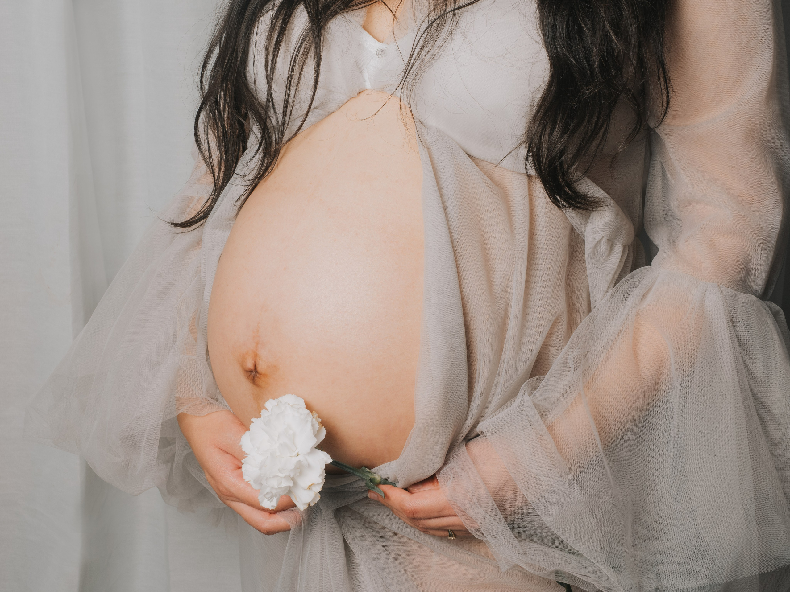 Ventre de femme enceinte avec fleur blanche