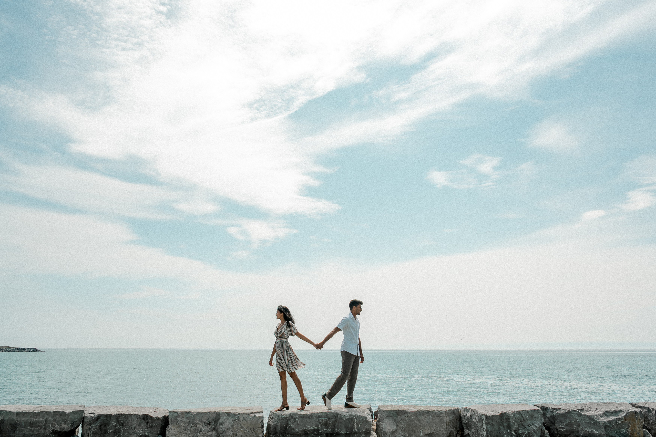 Couple walking hand in hand on a wooden boardwalk by the lake during their engagement photoshoot.
