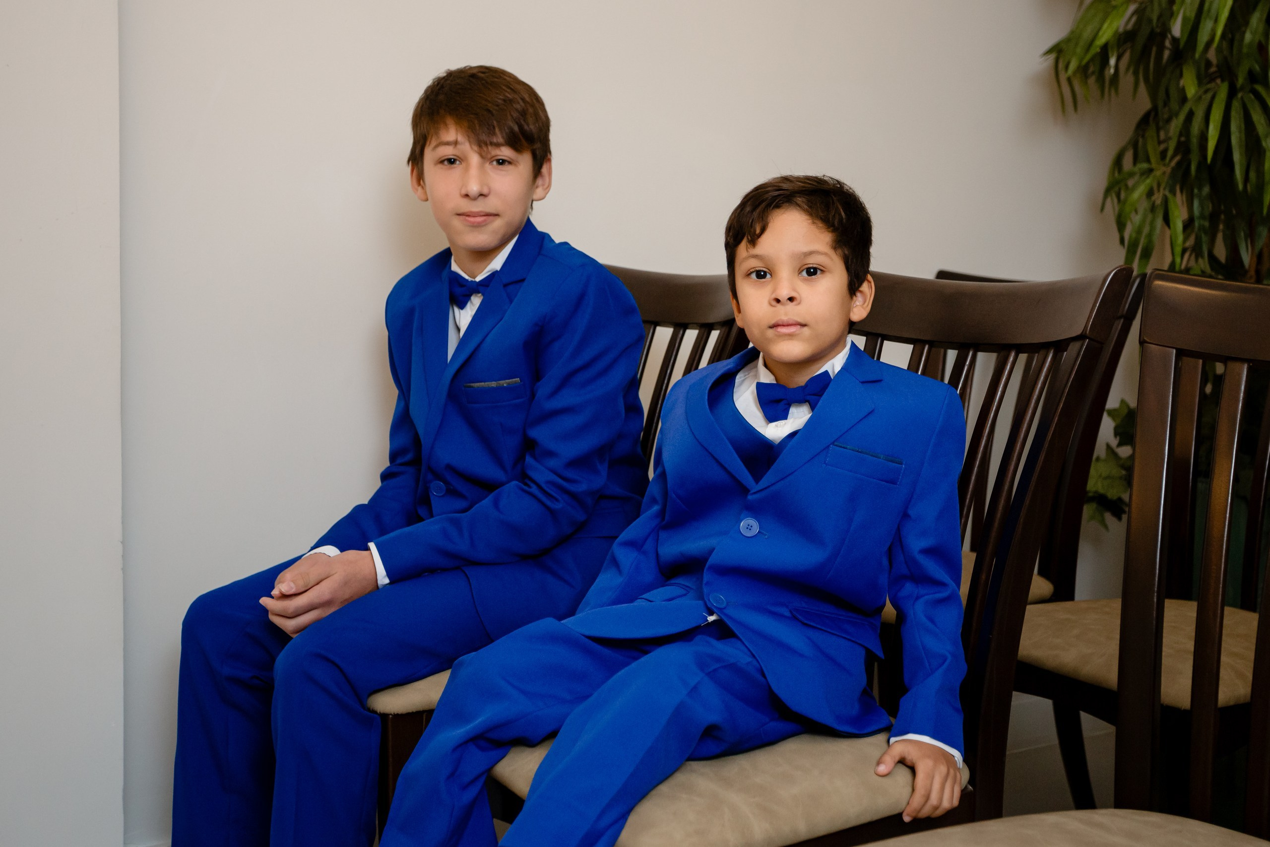 Fotógrafo de casamento civil em Navegantes; dois meninos elegantes vestidos com ternos azuis e gravatas-borboleta sentados durante a cerimônia de casamento.