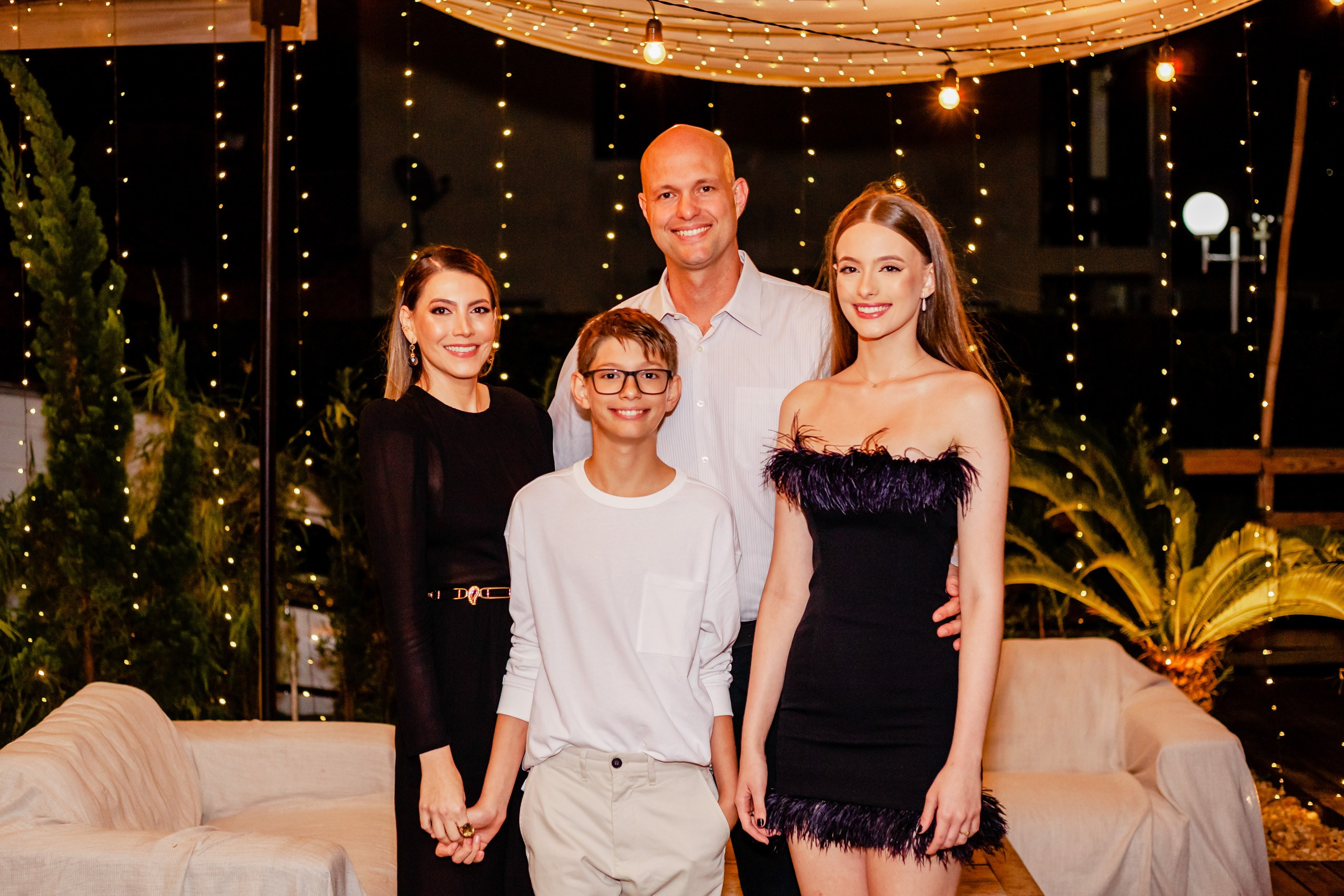 Fotógrafo festa de aniversário em Itajaí; retrato de família com a aniversariante sorridente em festa com iluminação noturna decorativa.