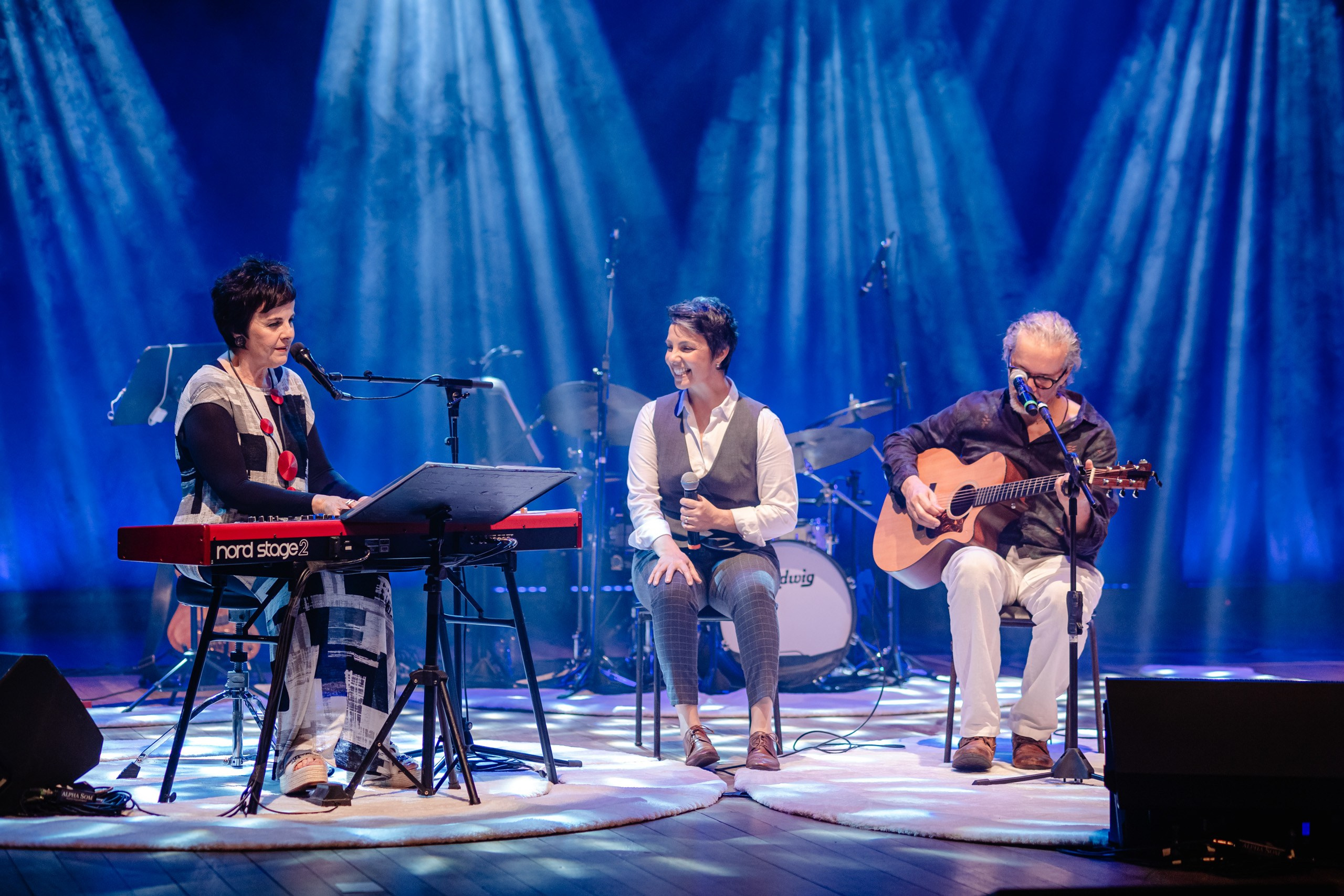 Show musical com grupo cantando no palco.