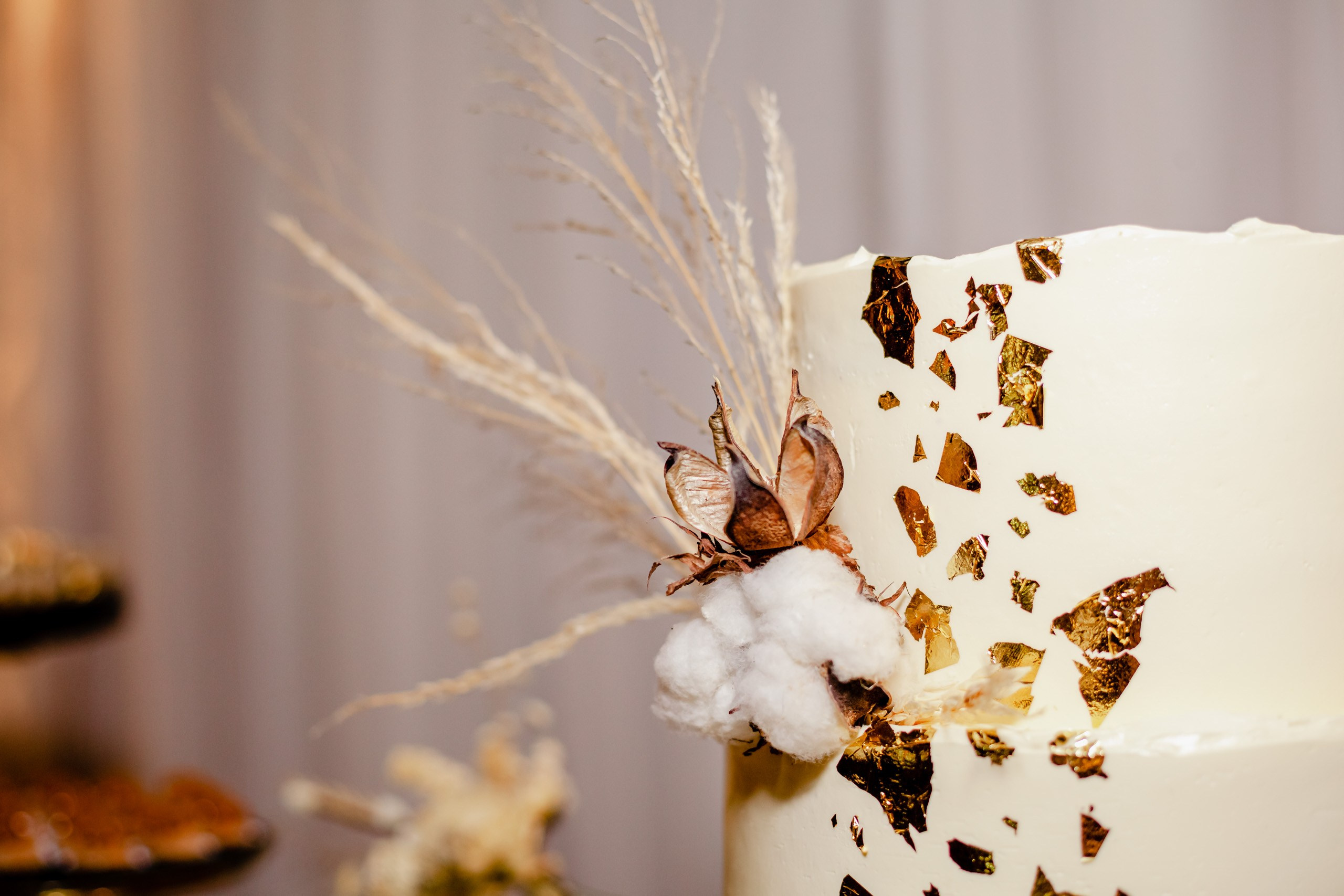 Fotógrafo festa de aniversário em Itajaí; detalhe do bolo decorado com folha de ouro e arranjo floral rústico em festa elegante na região.