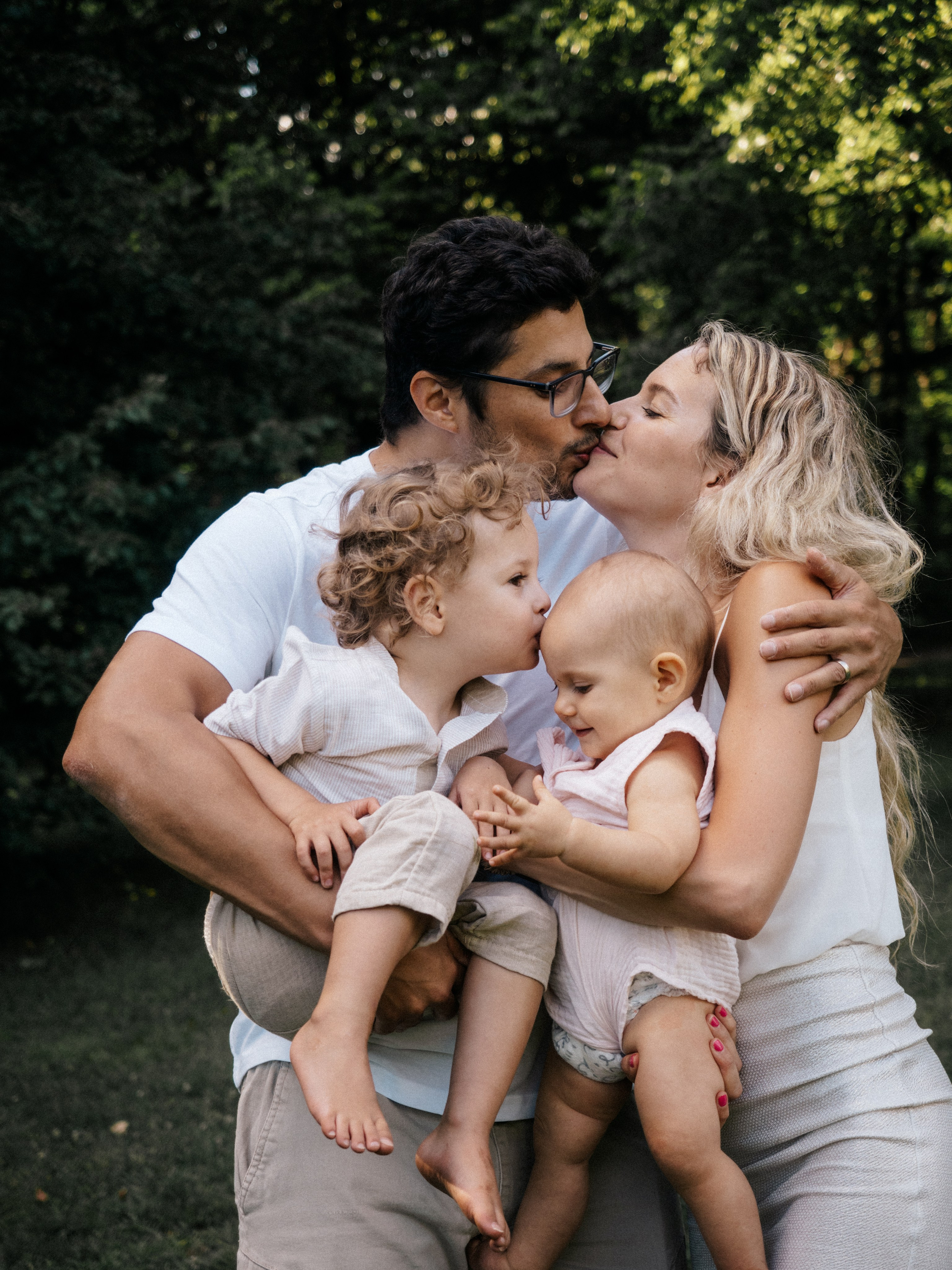 Family of four hugging and kissing for their family session.