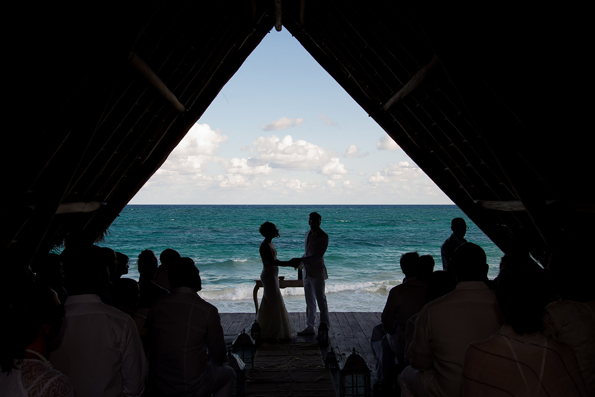 Bride and groom under triangular gazebo at sunset during destination wedding in Tulum, Mexico