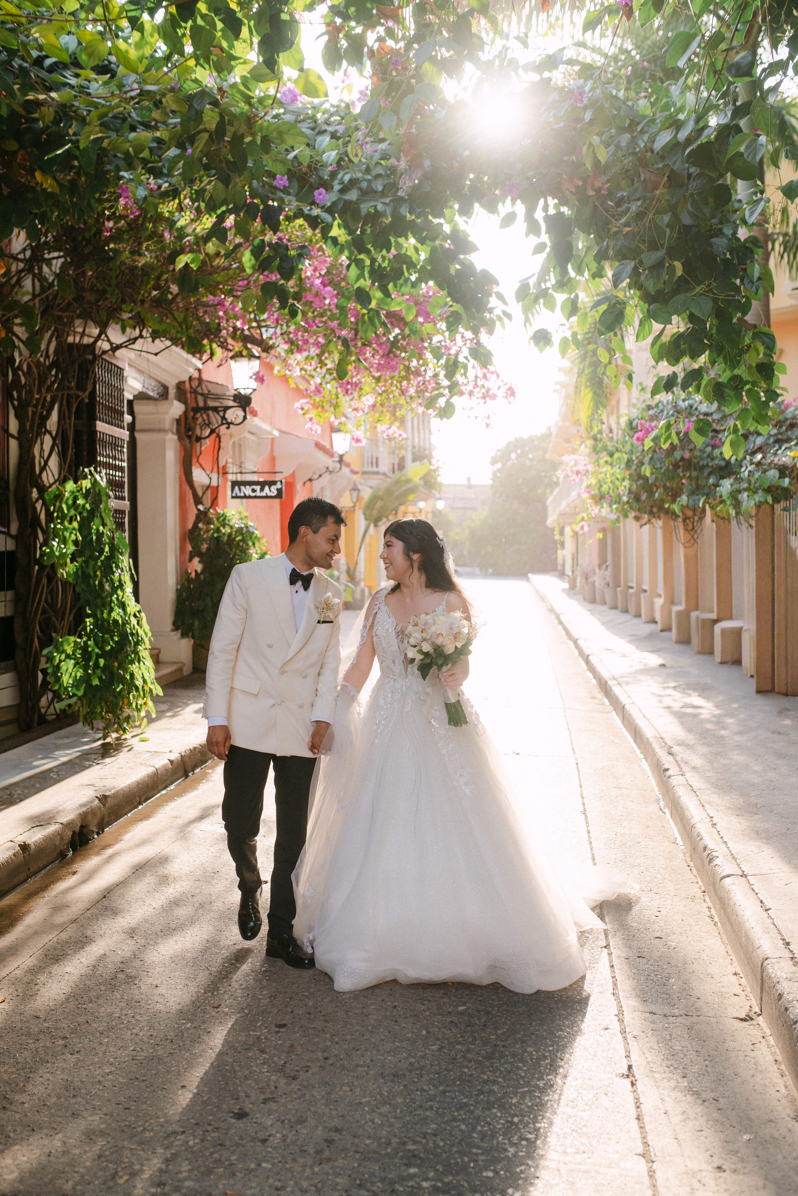 Couple walking down street – “Bride and groom walking together on a cobblestone street, wedding photoshoot in Cartagena