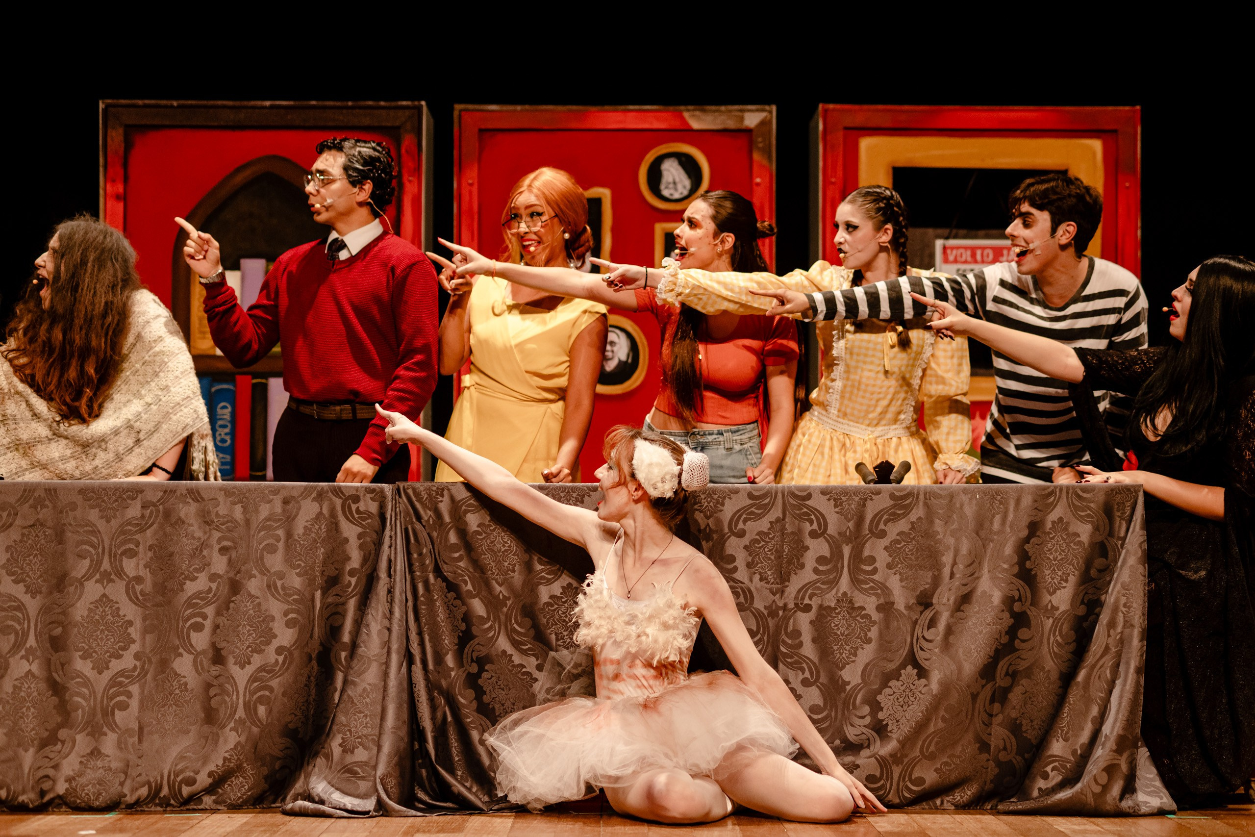 Apresentação teatral com grupo de pessoas apontando para o lado.