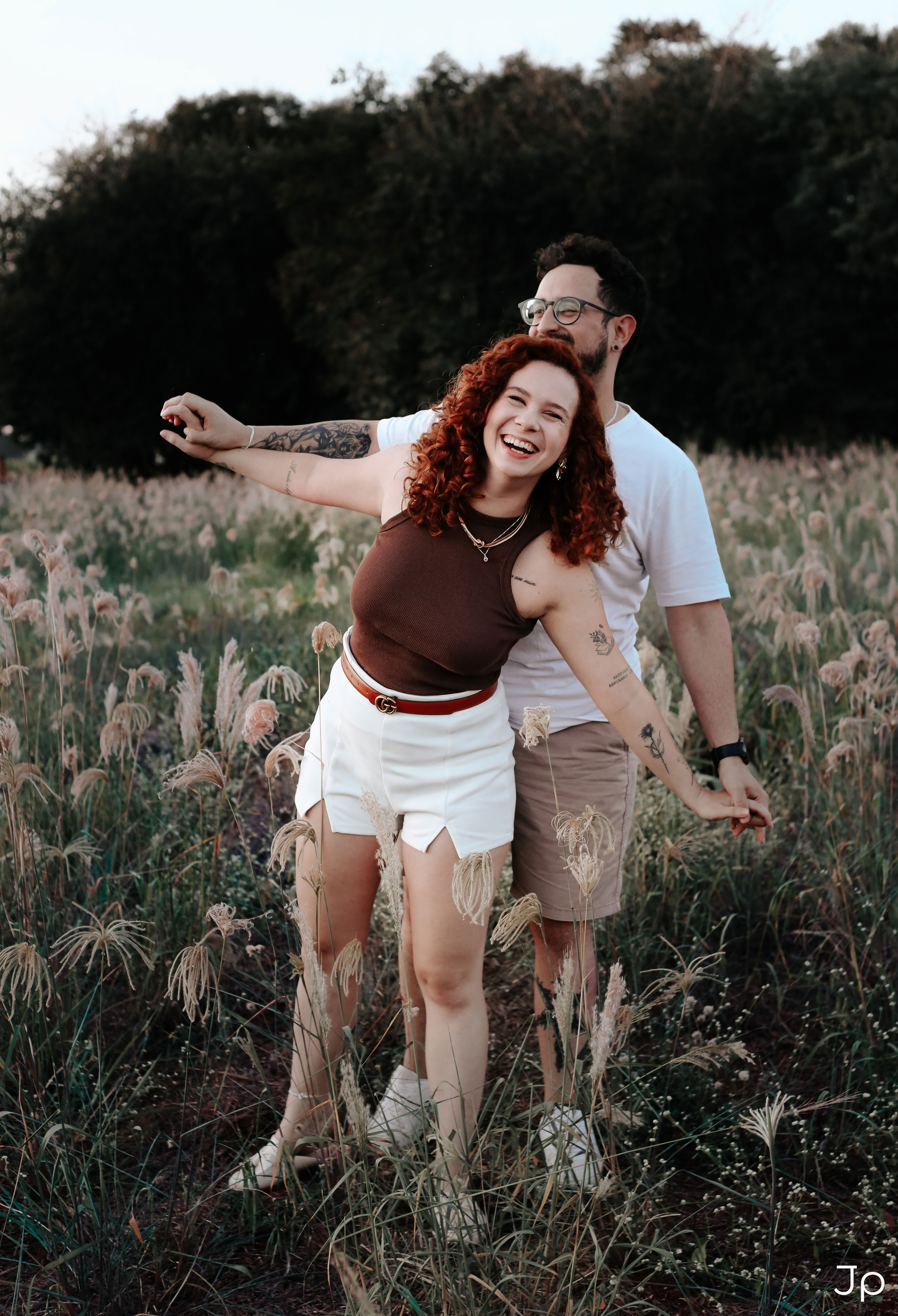 Casal brincando no campo, rindo juntos.
