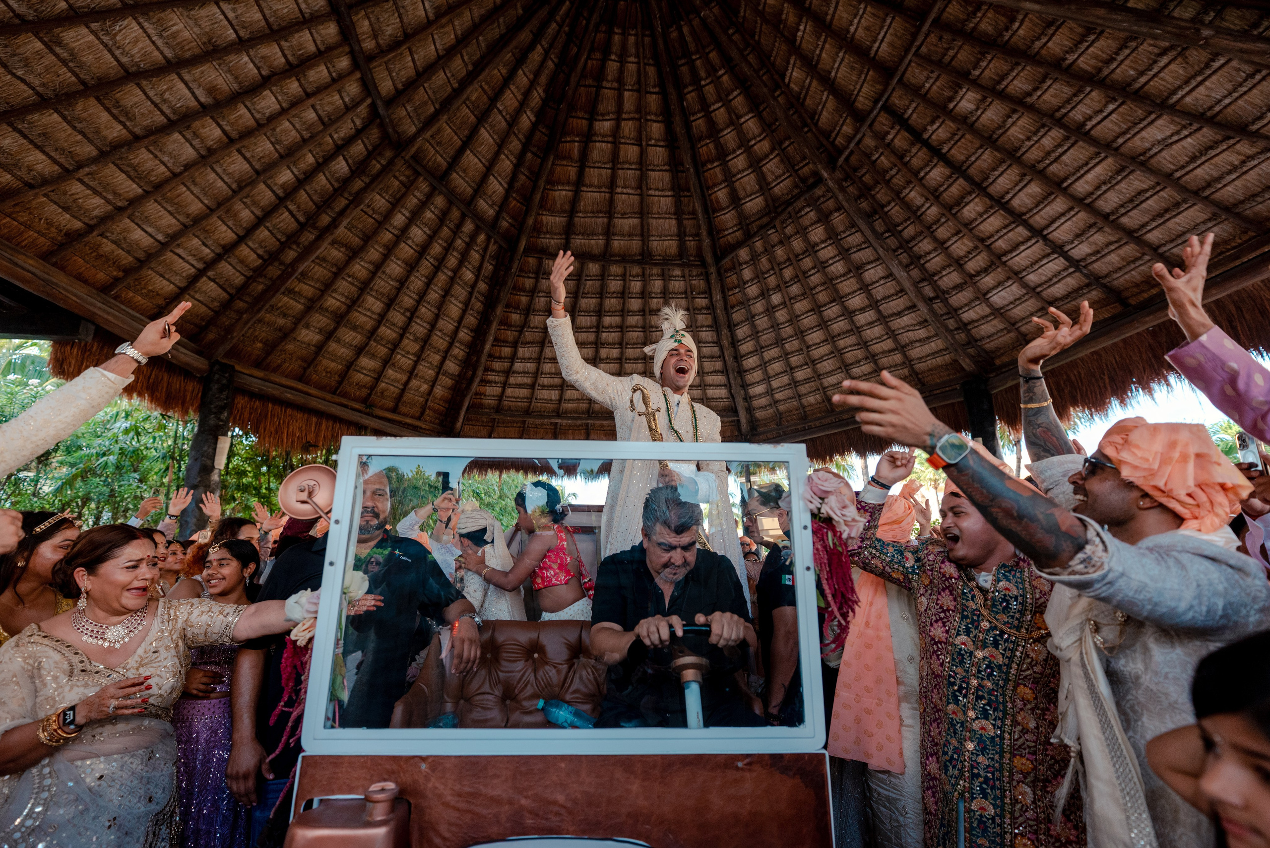 Indian wedding groom celebrating on a decorated car during the Baraat procession in Cancun Mexico