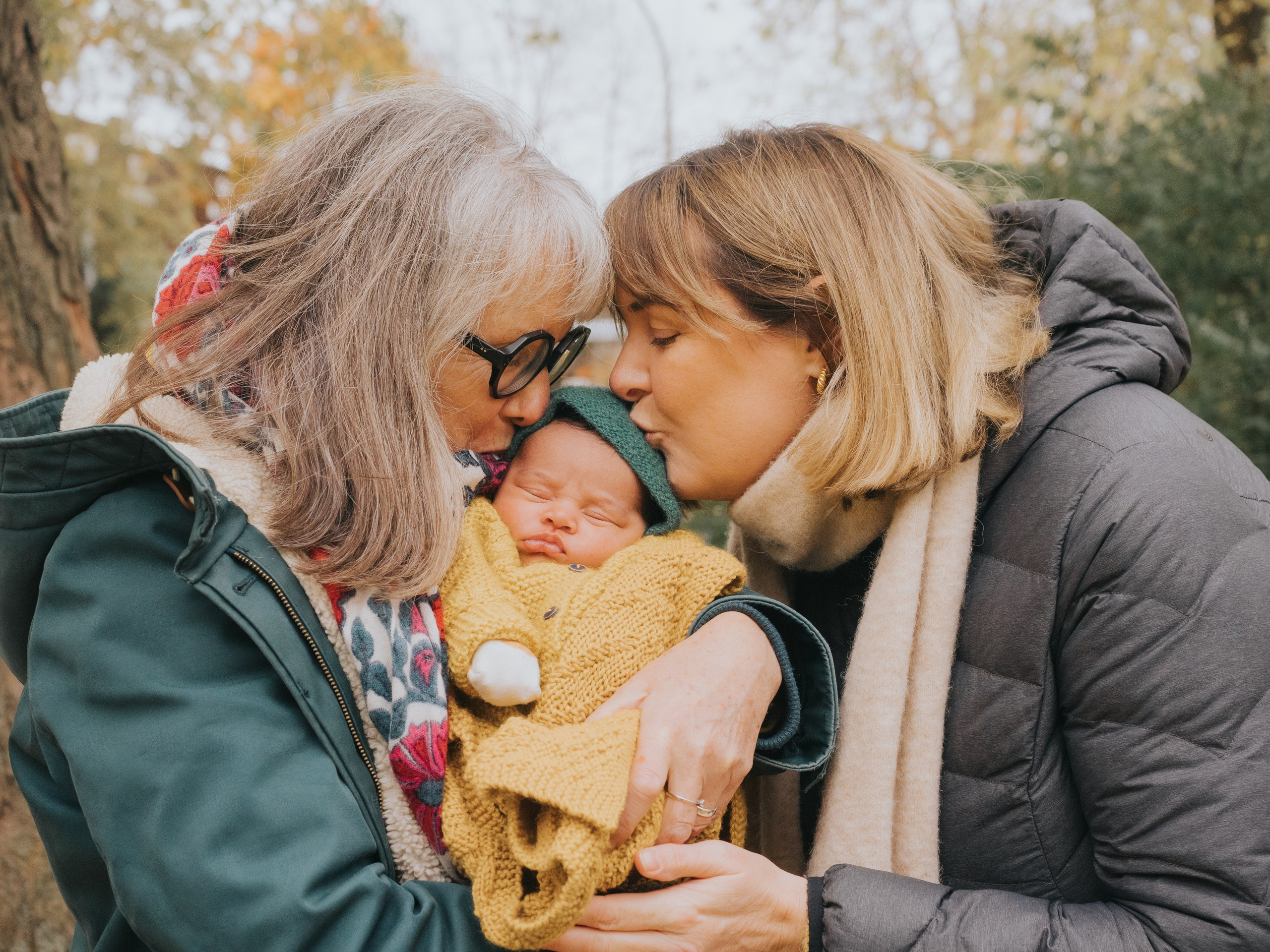 Mother and grandmother kissing newborn.