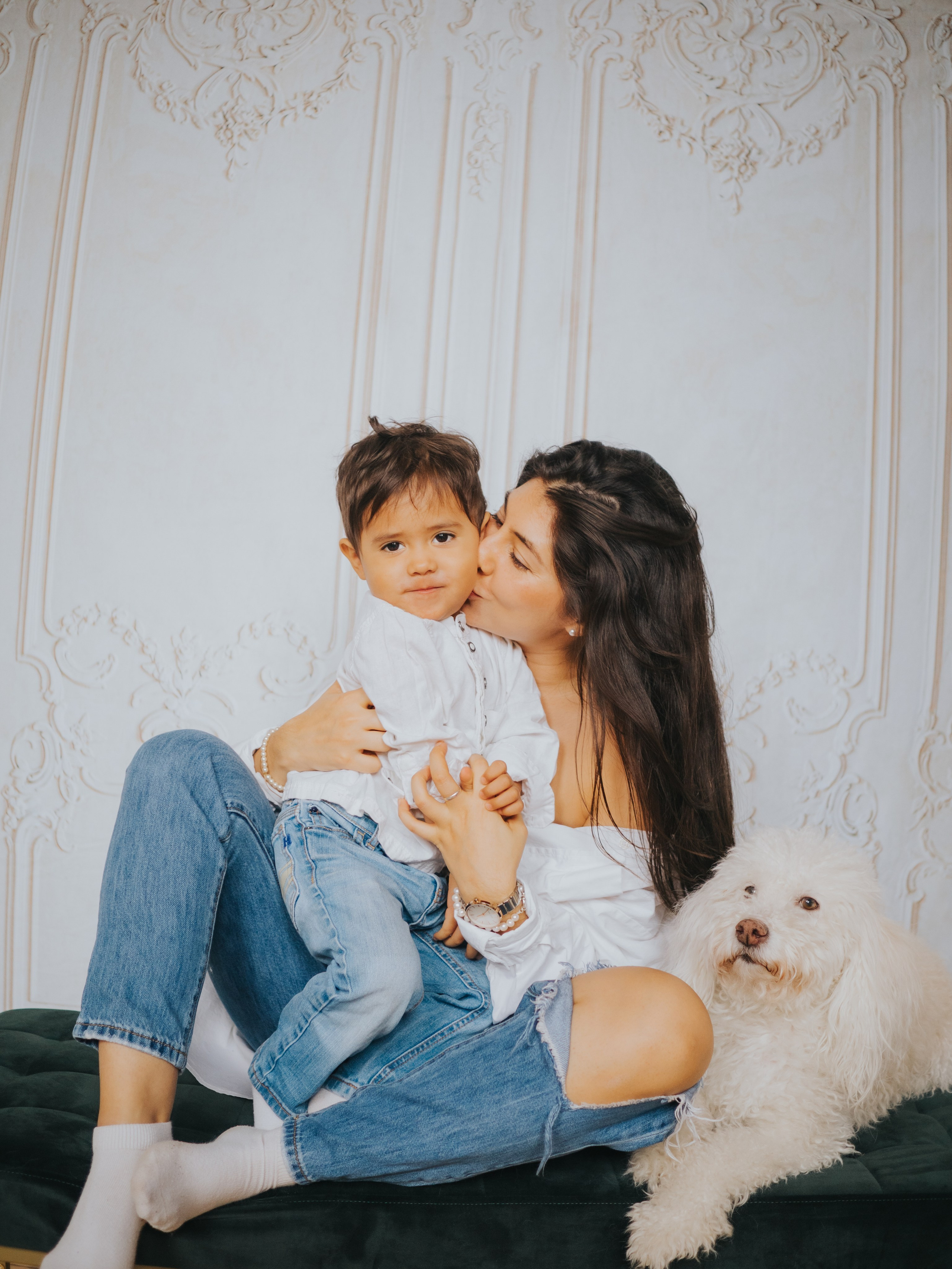 Maman, fils et chien devant mur avec moulures.