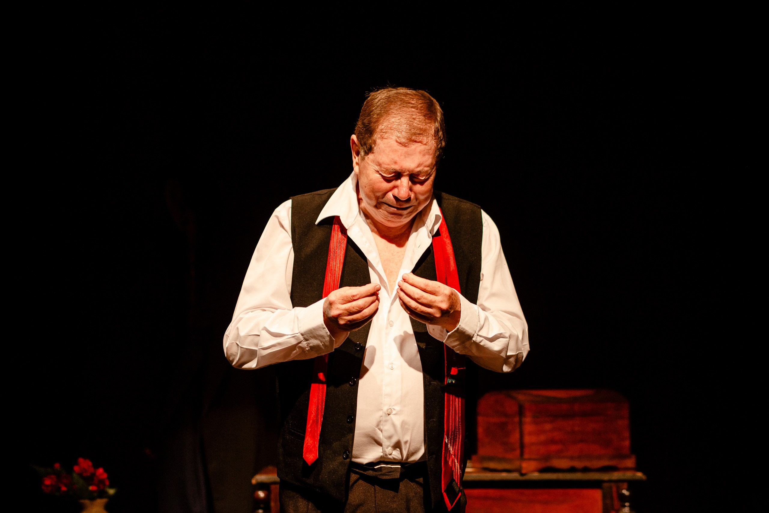Apresentação teatral com ator chorando no palco.