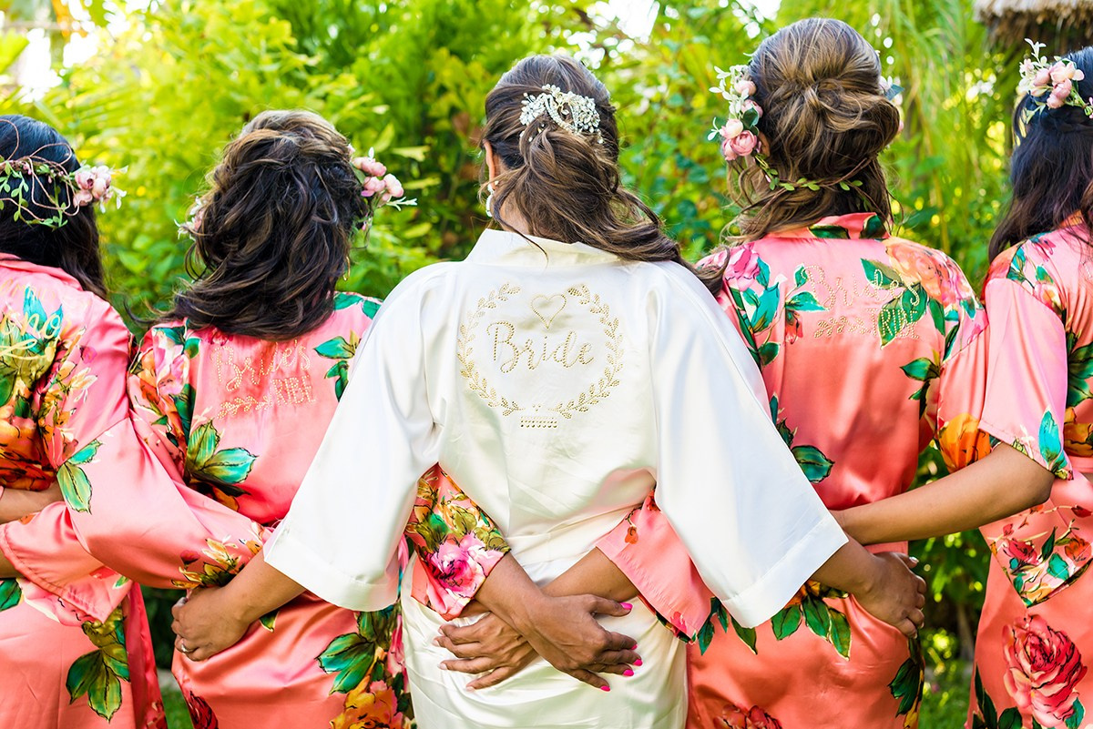 Bride hugging bridesmaids in robes before wedding ceremony in Los Cabos