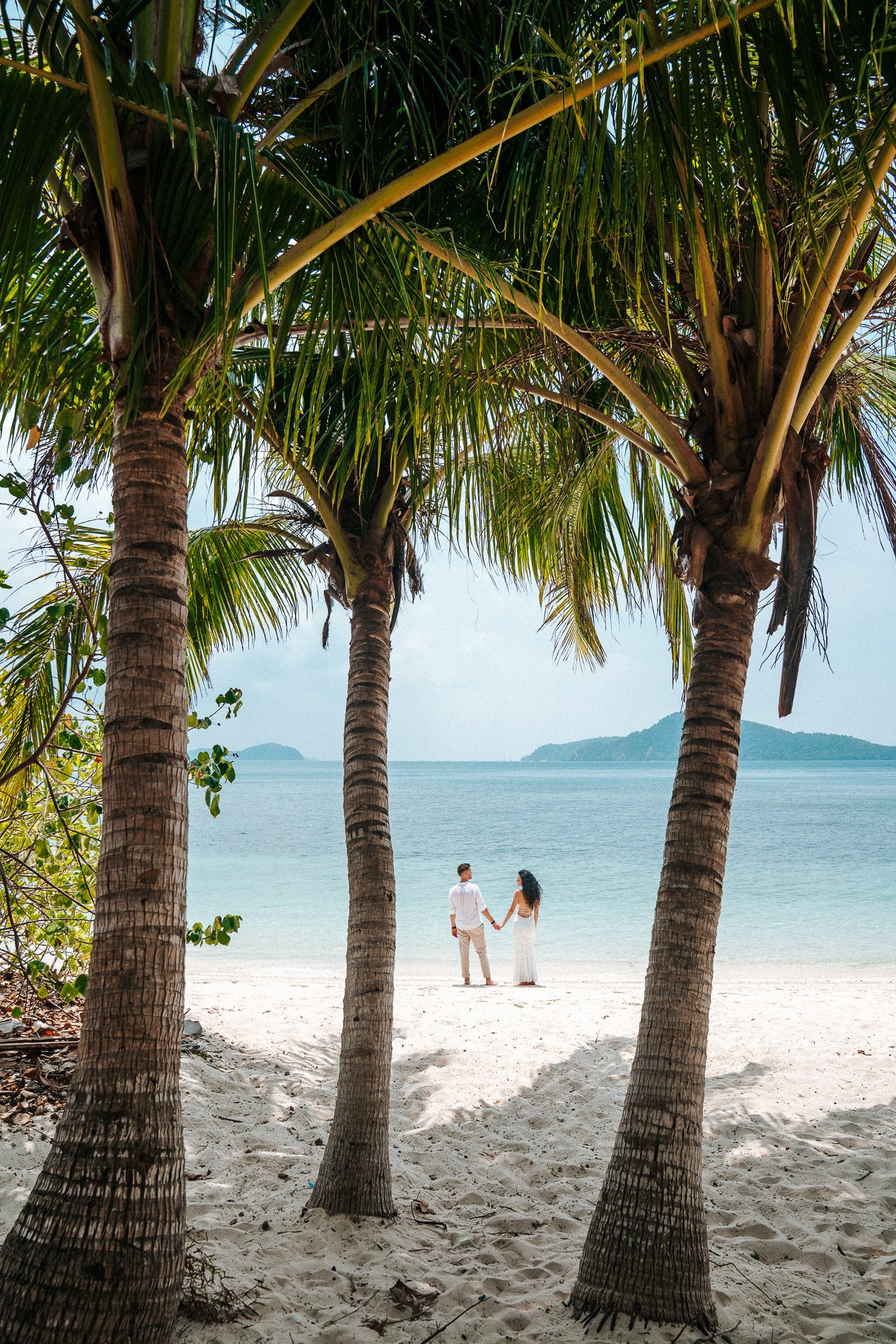 Romantic beach photography in Phuket featuring a couple surrounded by palm trees and tropical nature