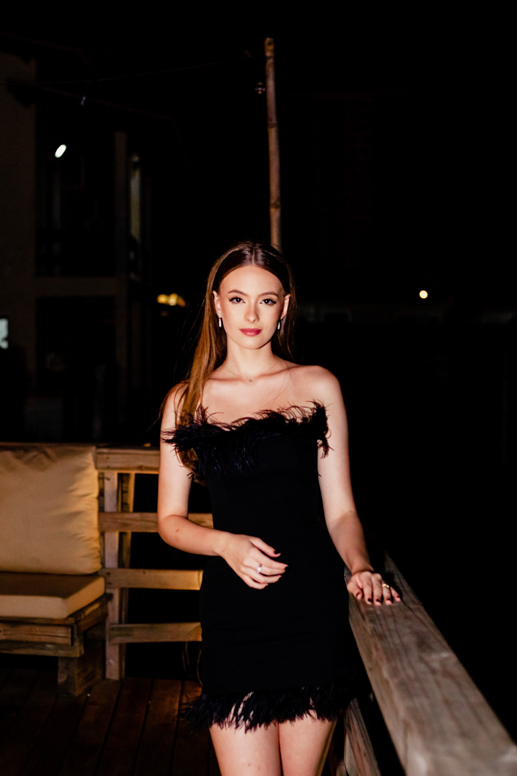 Fotógrafo festa de aniversário em Itajaí; retrato frontal e elegante da aniversariante sorrindo suavemente ao ar livre durante a comemoração noturna.