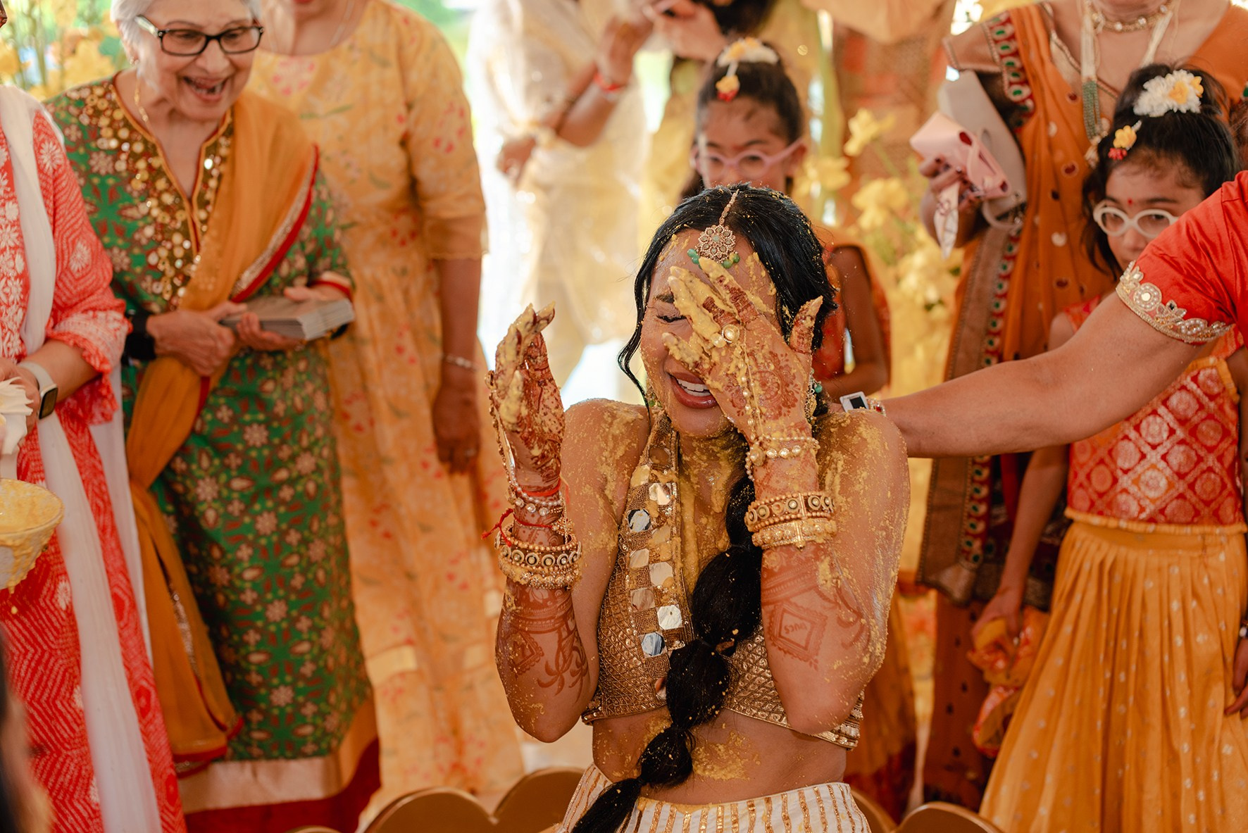 Indian bride laughing during Haldi ceremony surrounded by turmeric at a destination wedding in Riviera Maya