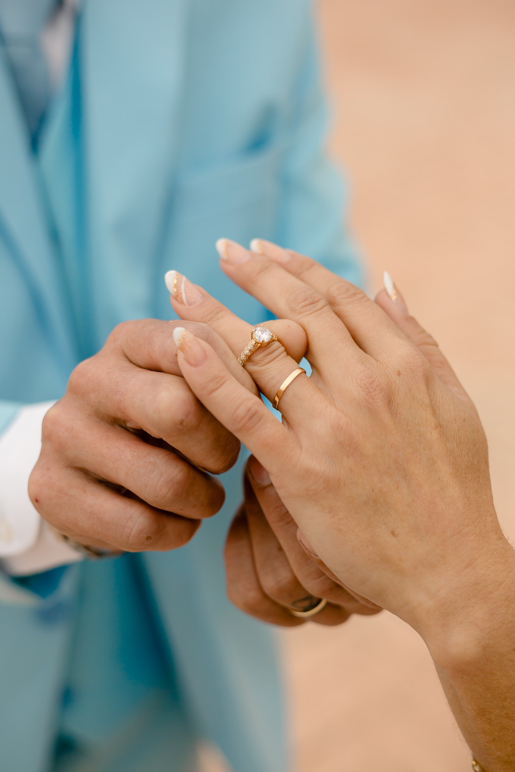 Fotógrafo de casamento em Navegantes; close macro detalhado das mãos do casal ajustando as alianças e o anel de noivado durante ensaio externo.