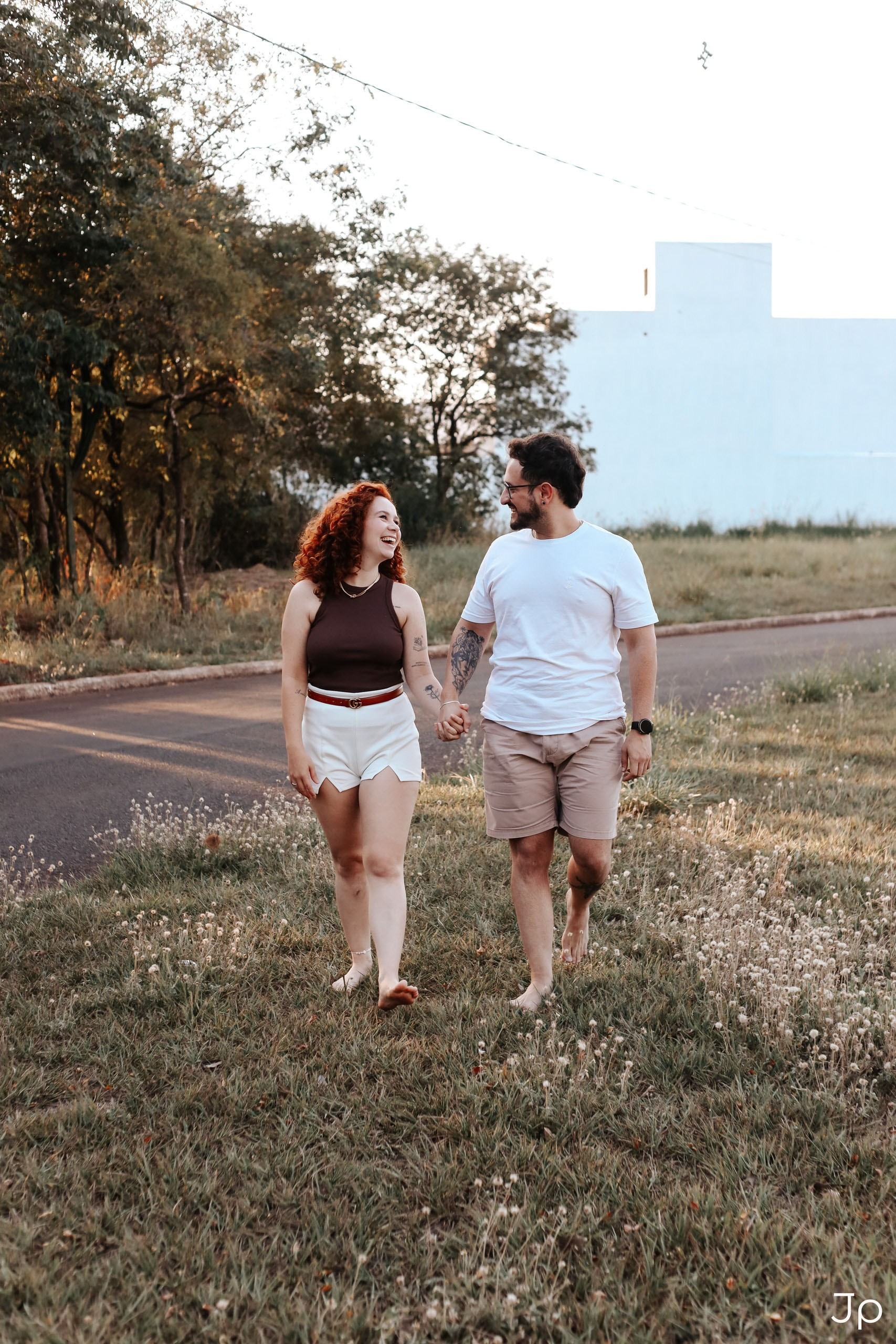 Casal caminhando de mãos dadas no gramado.