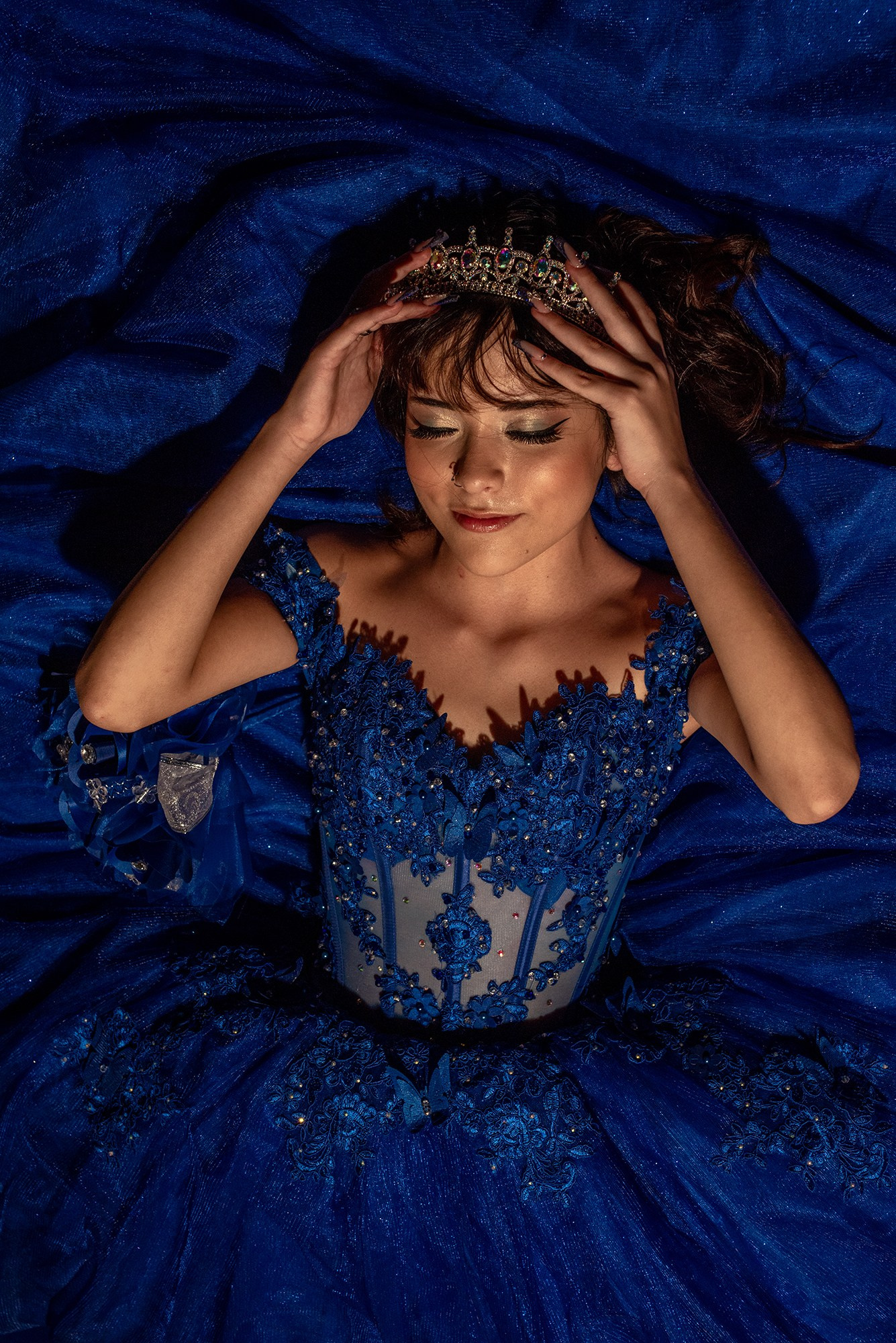 Quinceañera photography Los Cabos – Michelle in blue quince dress adjusting her crown, elegant sweet fifteen beach portraits at sunset, Cabo San Lucas XV años destination session.