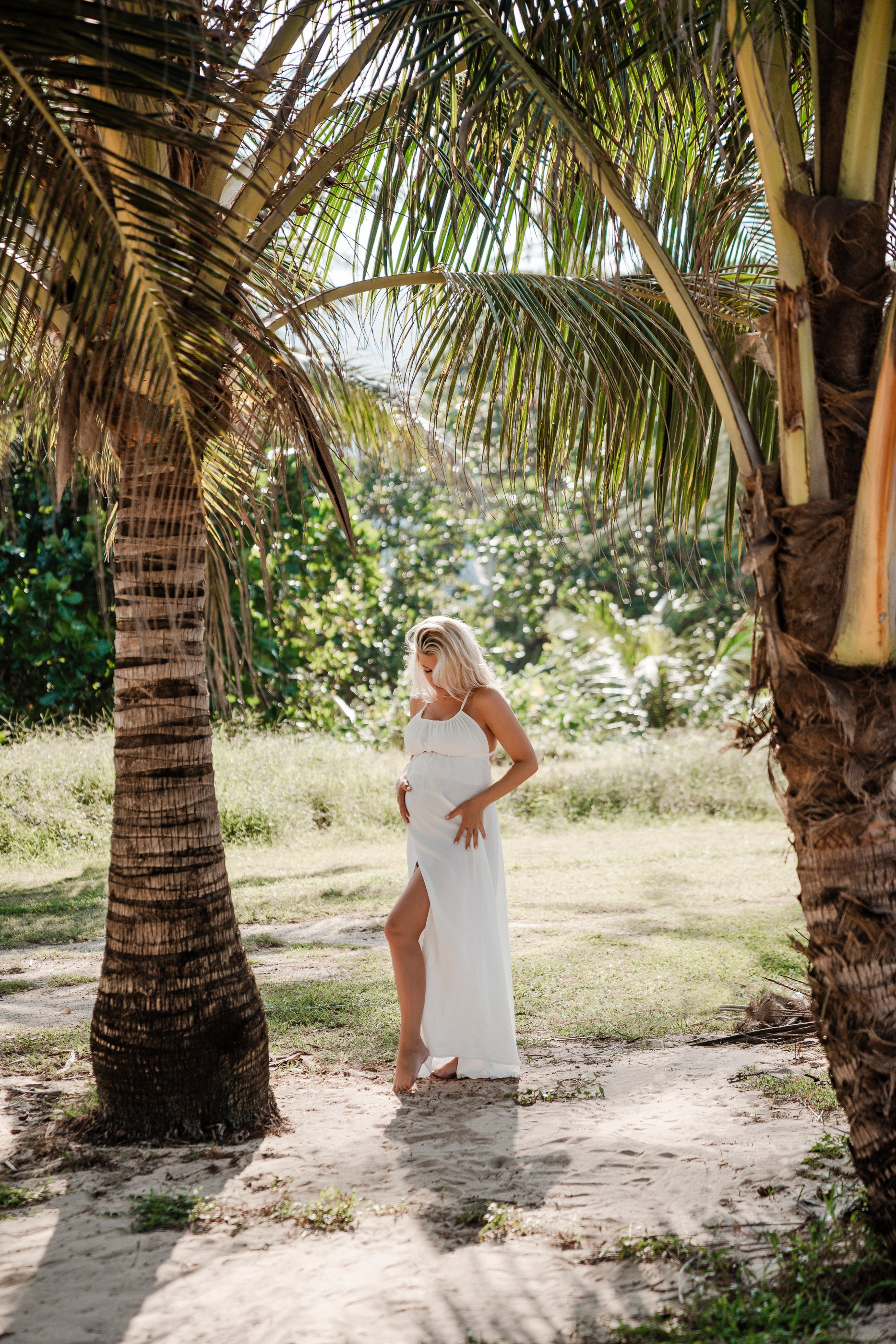 Luxury maternity photography on a Phuket beach with palm trees and mountain views