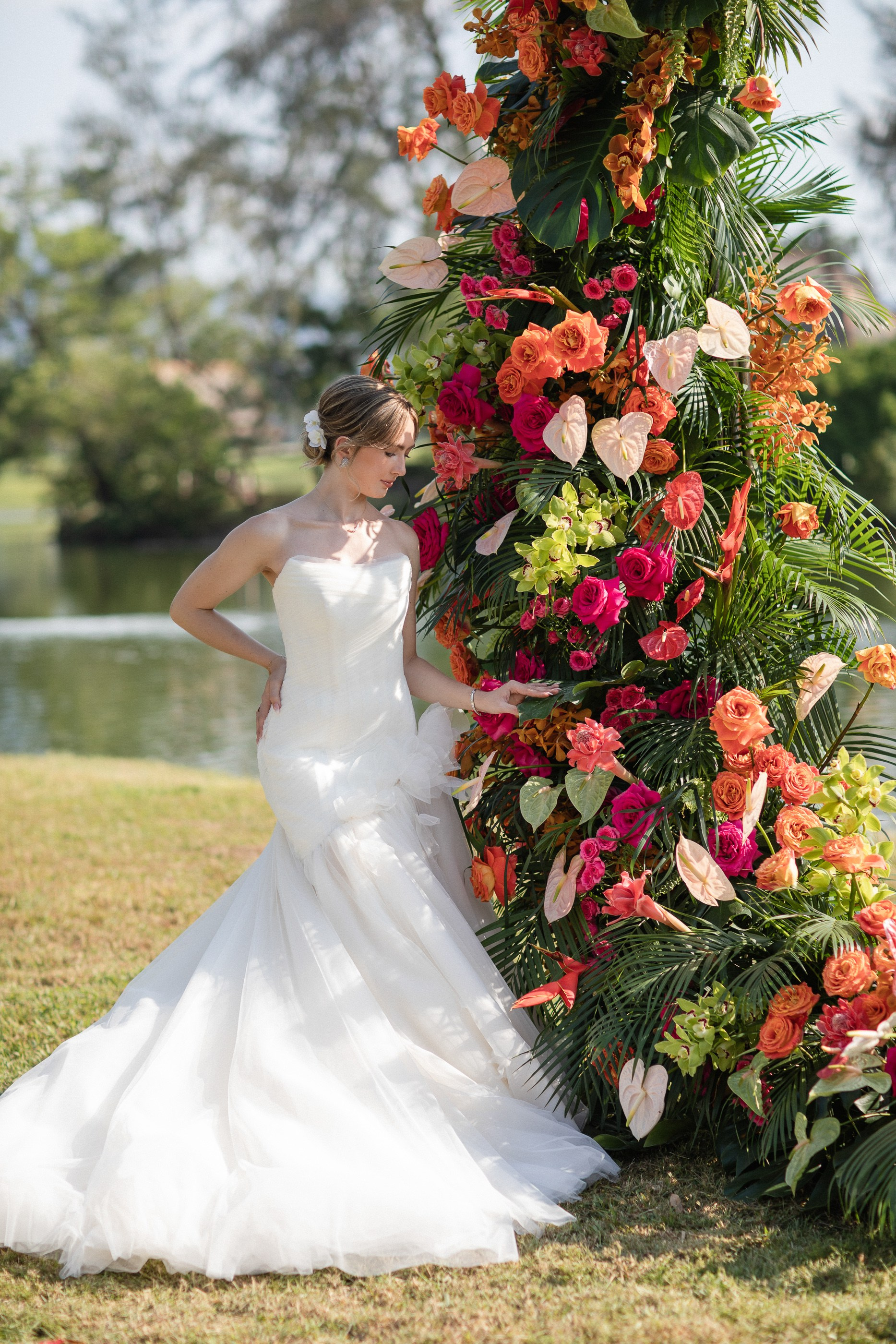 Luxury beach wedding photography in Phuket with a bride by the arch surrounded by tropical scenery