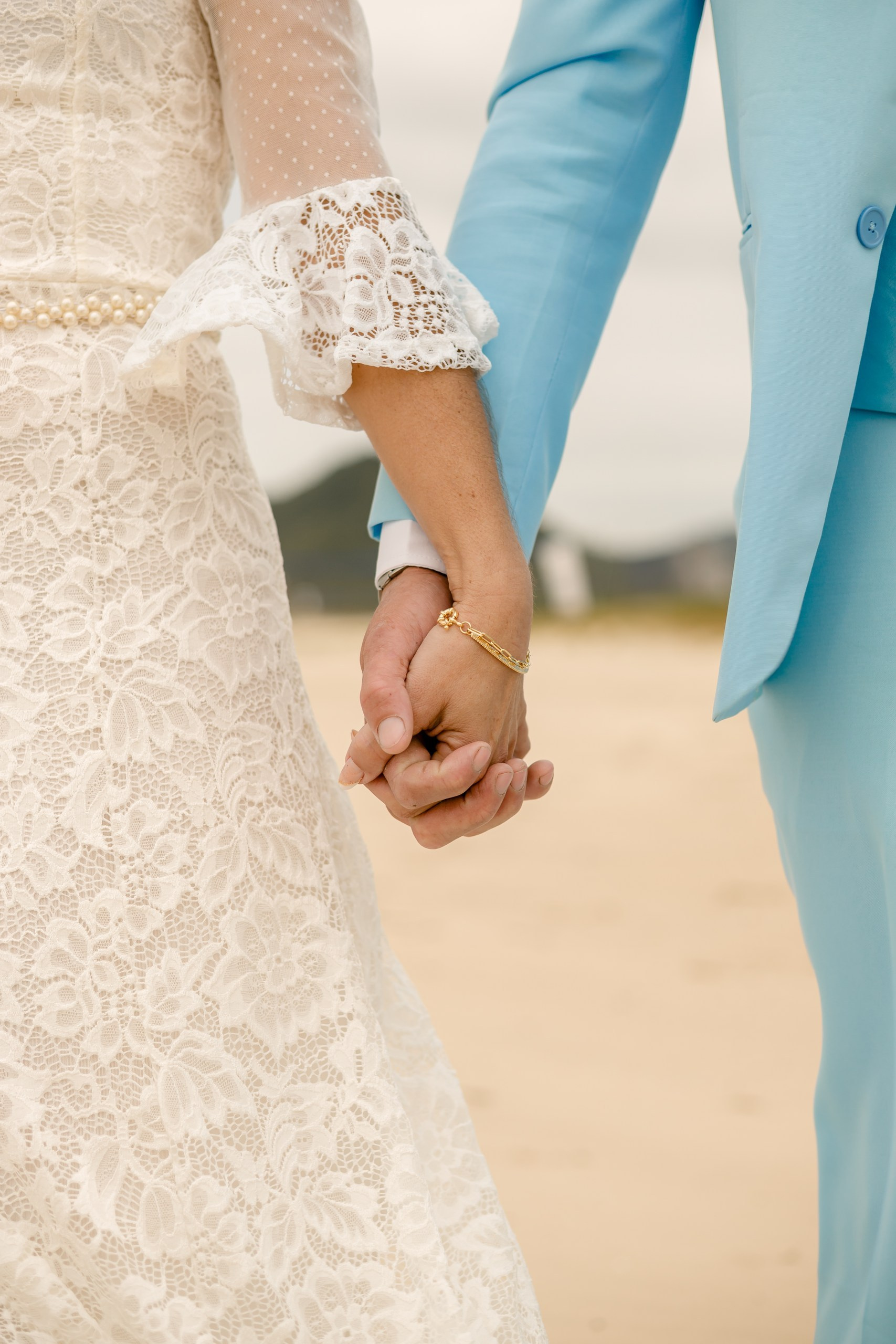 Fotógrafo de casamento em Navegantes; close detalhado das mãos dadas do casal durante o ensaio externo na praia.