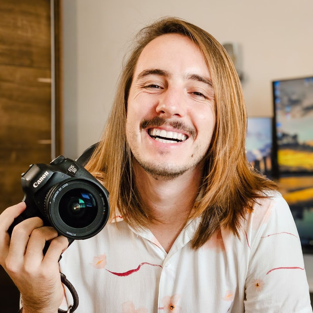 Fotógrafo com a câmera na mão e sorrindo.