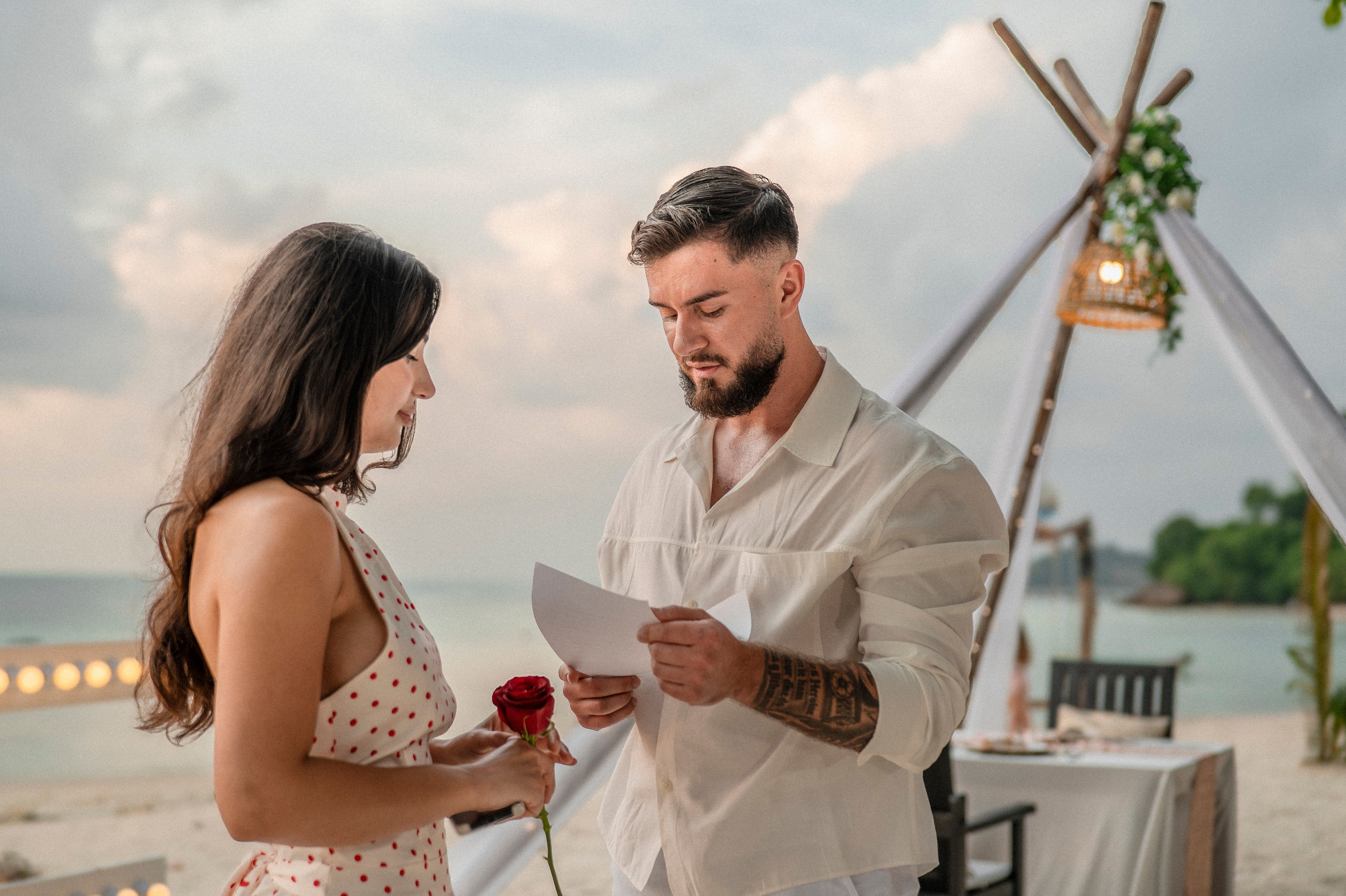 Romantic couple celebrating their engagement on a Pattaya beach beside an elegant proposal setup.
