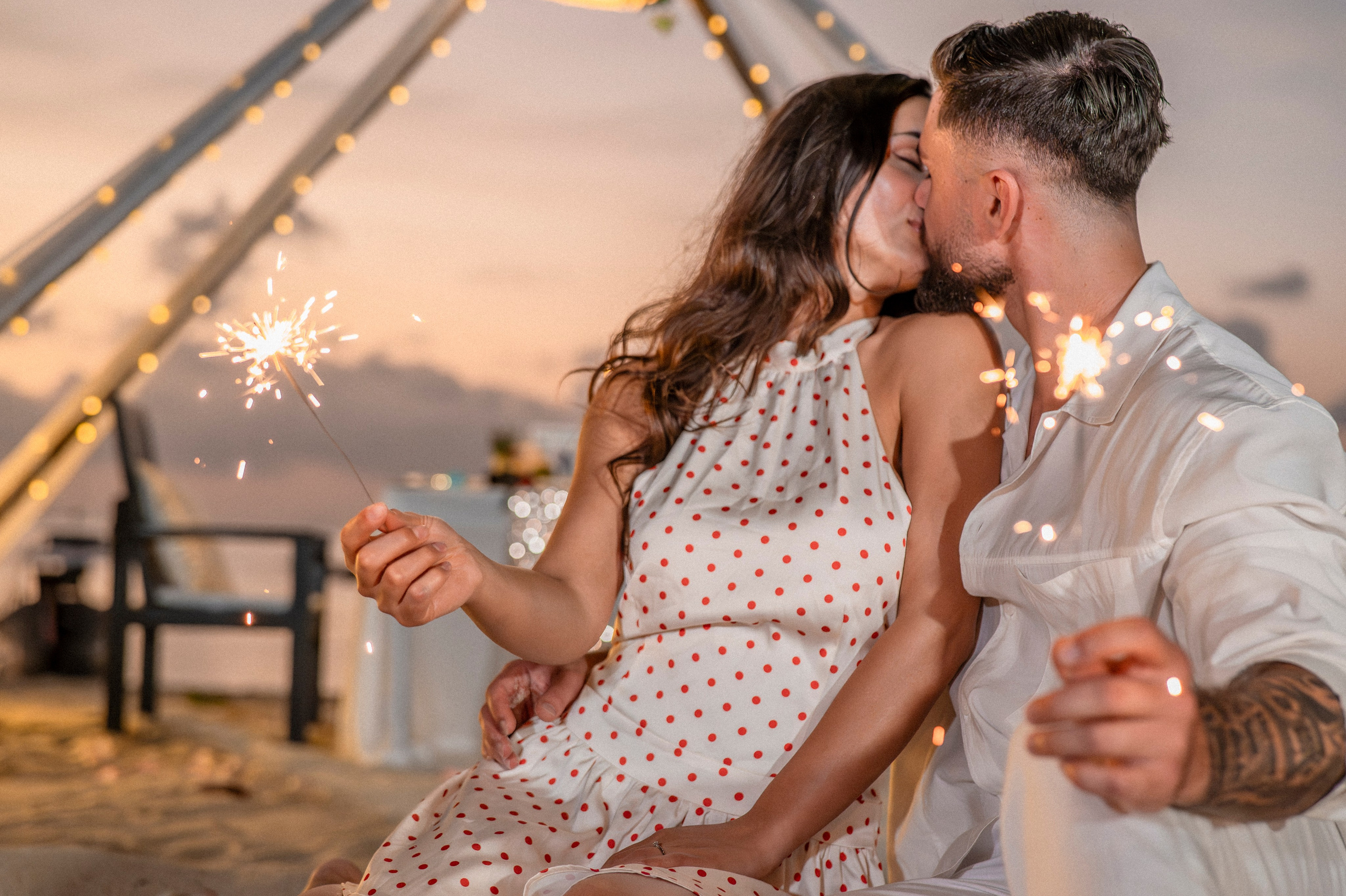 Newly engaged couple kissing beside a romantic beach proposal setup in Pattaya.