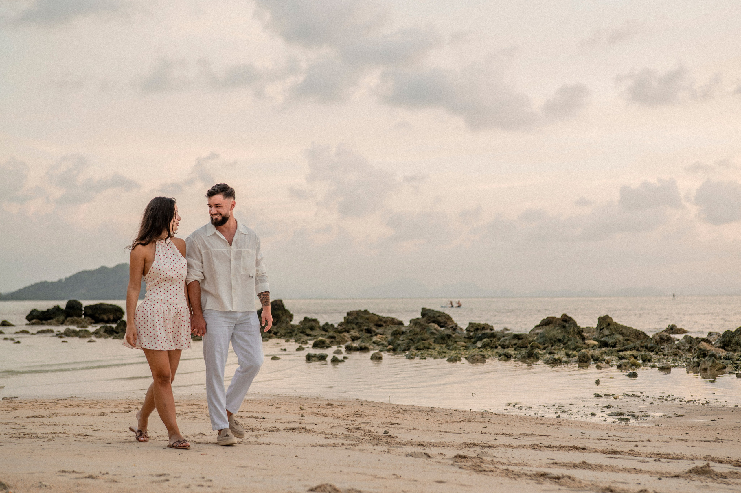 Engaged couple walking together along a Pattaya beach after their romantic marriage proposal.