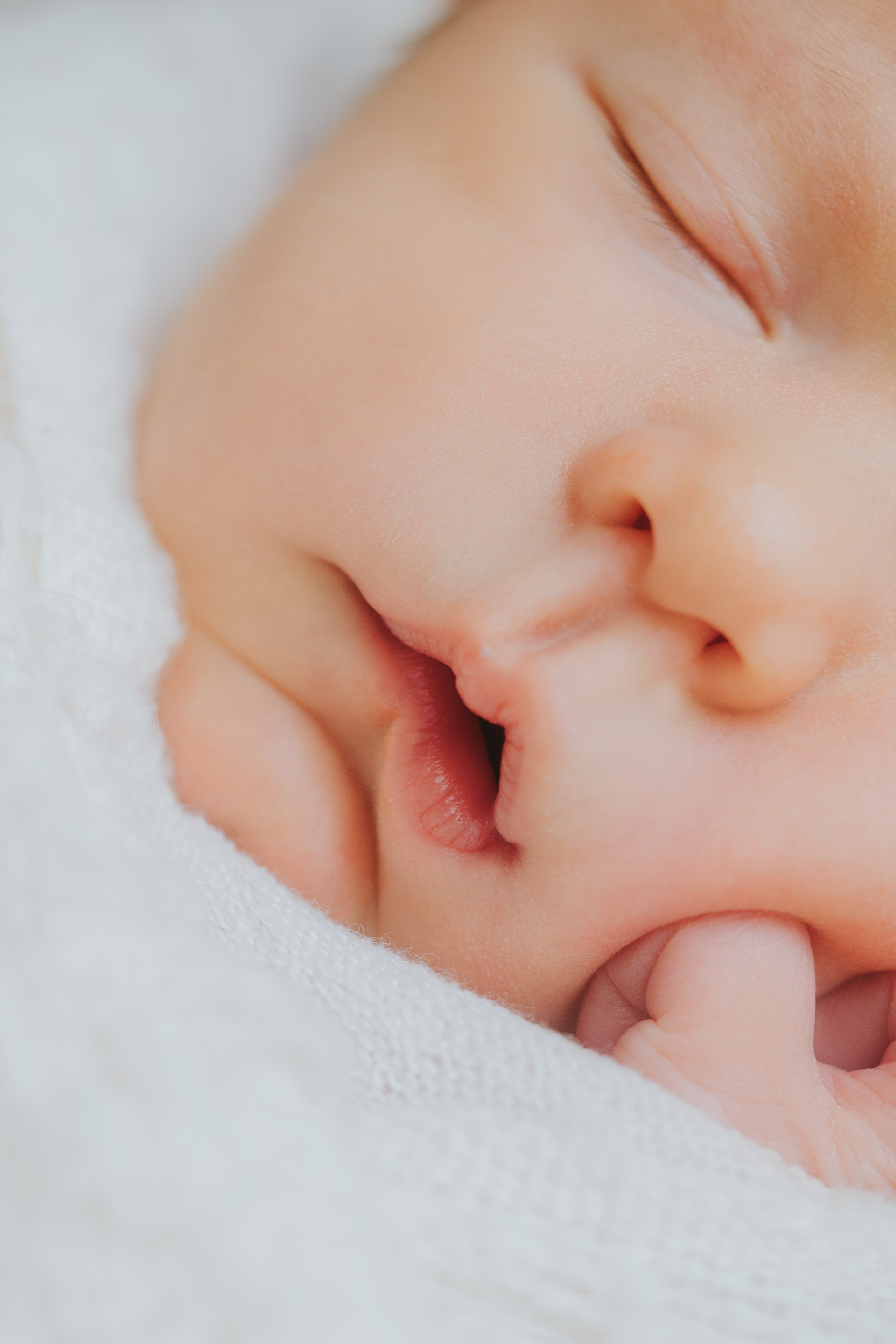 Minimalist newborn photo with natural window light and white wrap, Montreal newborn photographer.