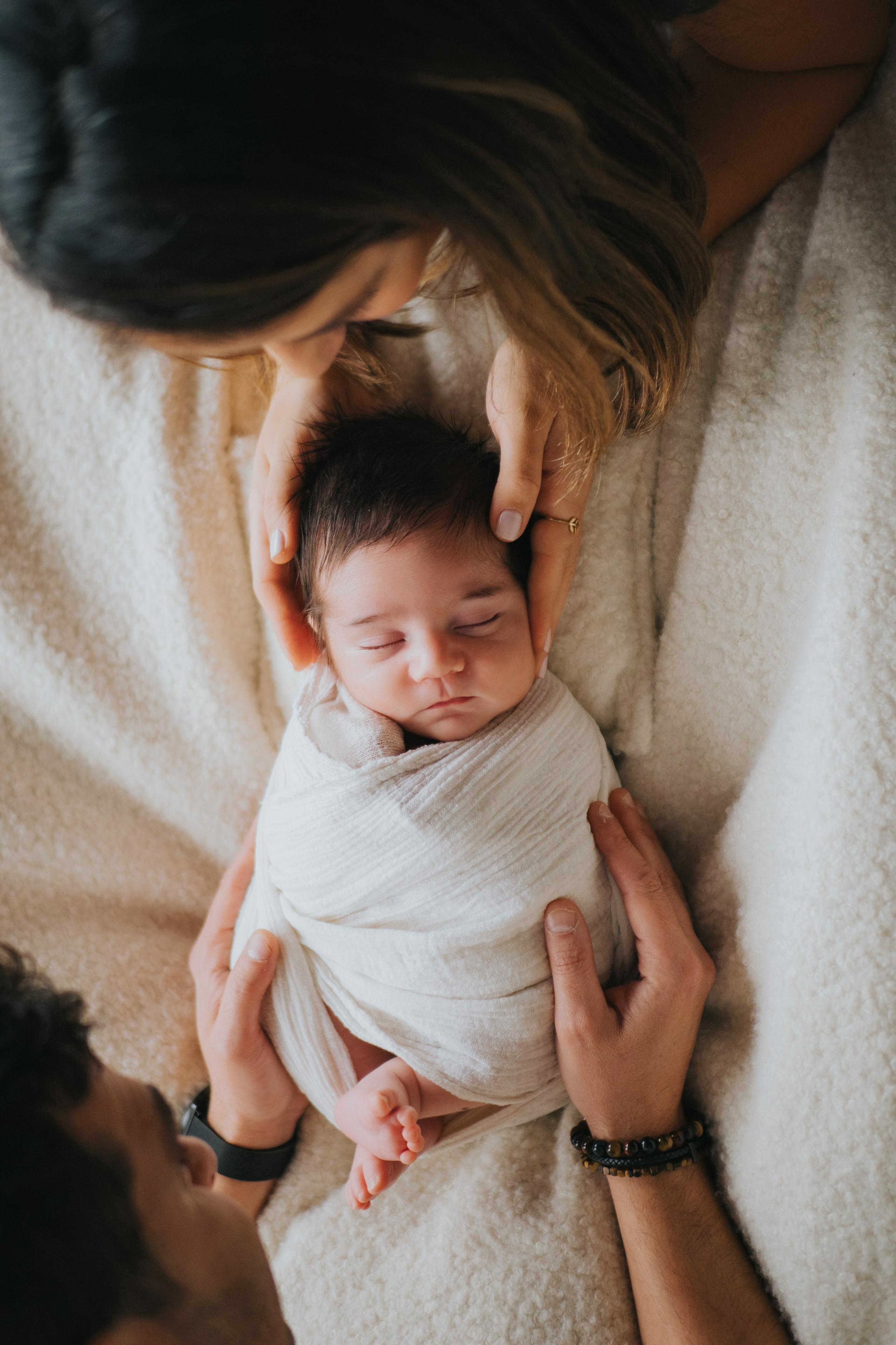 Natural light newborn session with white wrap and parent hands, Mimosa Studios Montreal.