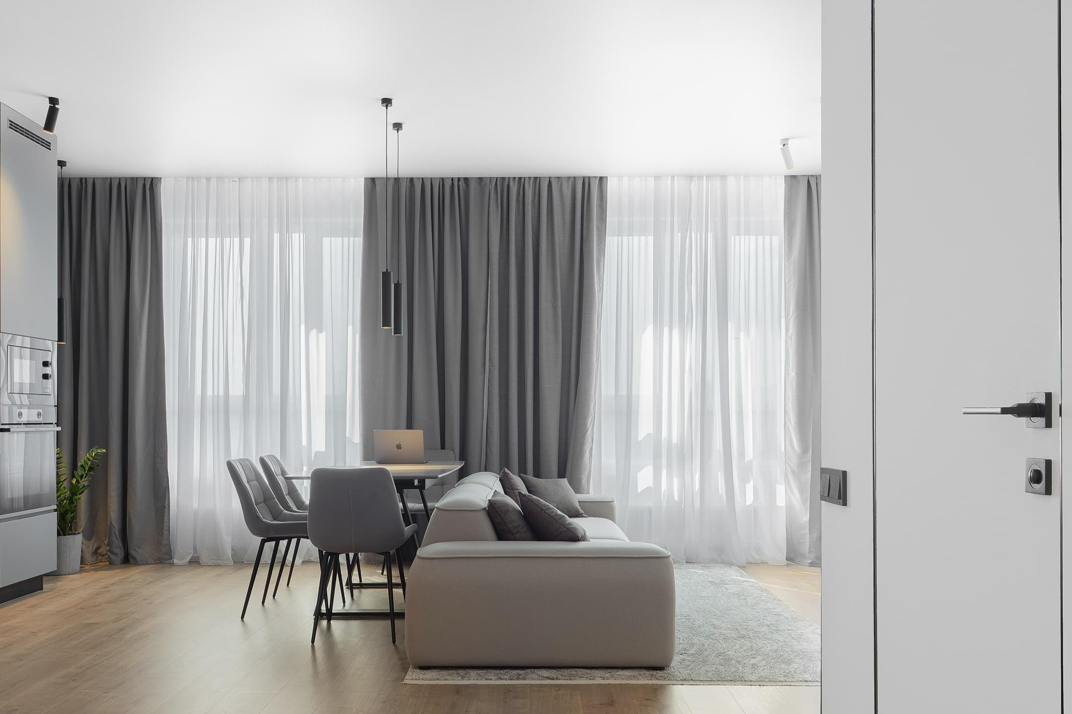 Photographie d’un intérieur moderne — salon et salle à manger avec rideaux gris.