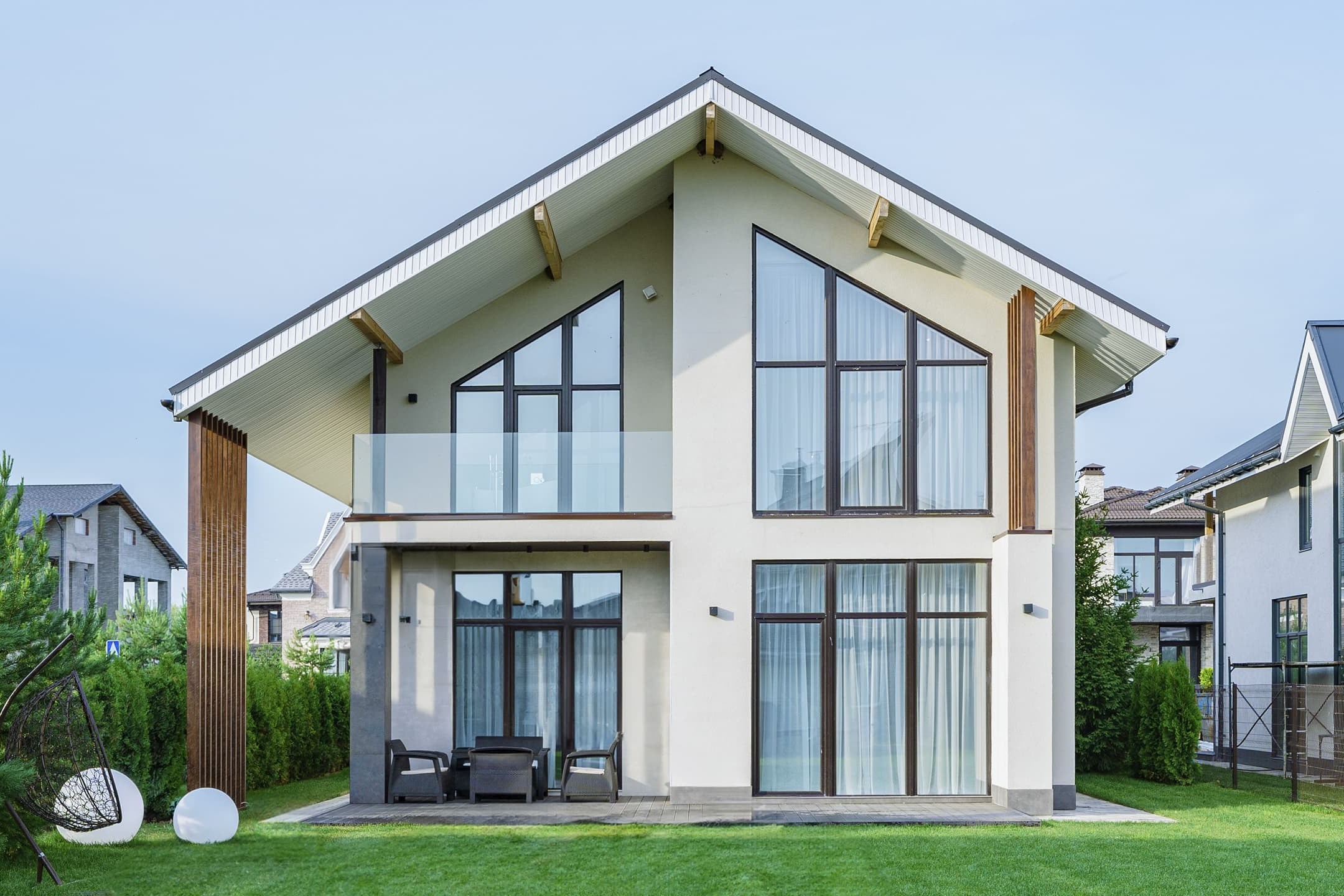Photographie d’une maison moderne avec grandes fenêtres et jardin.