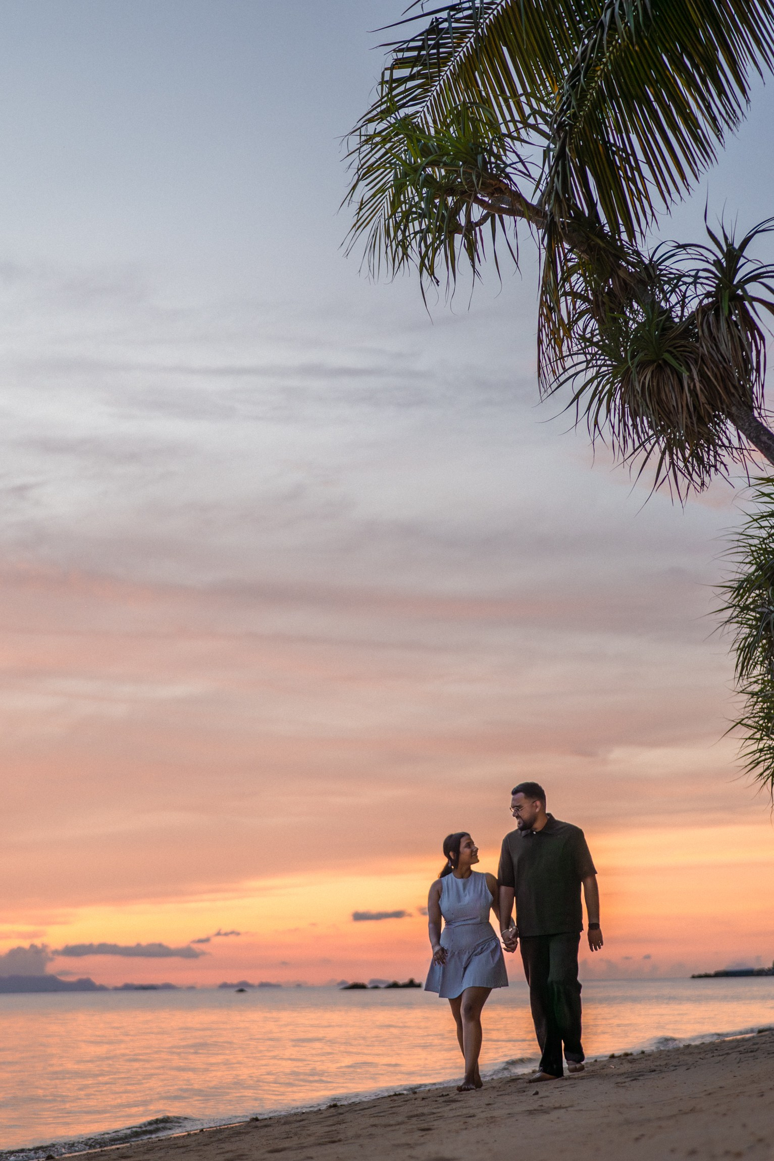 Romantic couple standing together by the sea at sunset after their proposal in Pattaya.