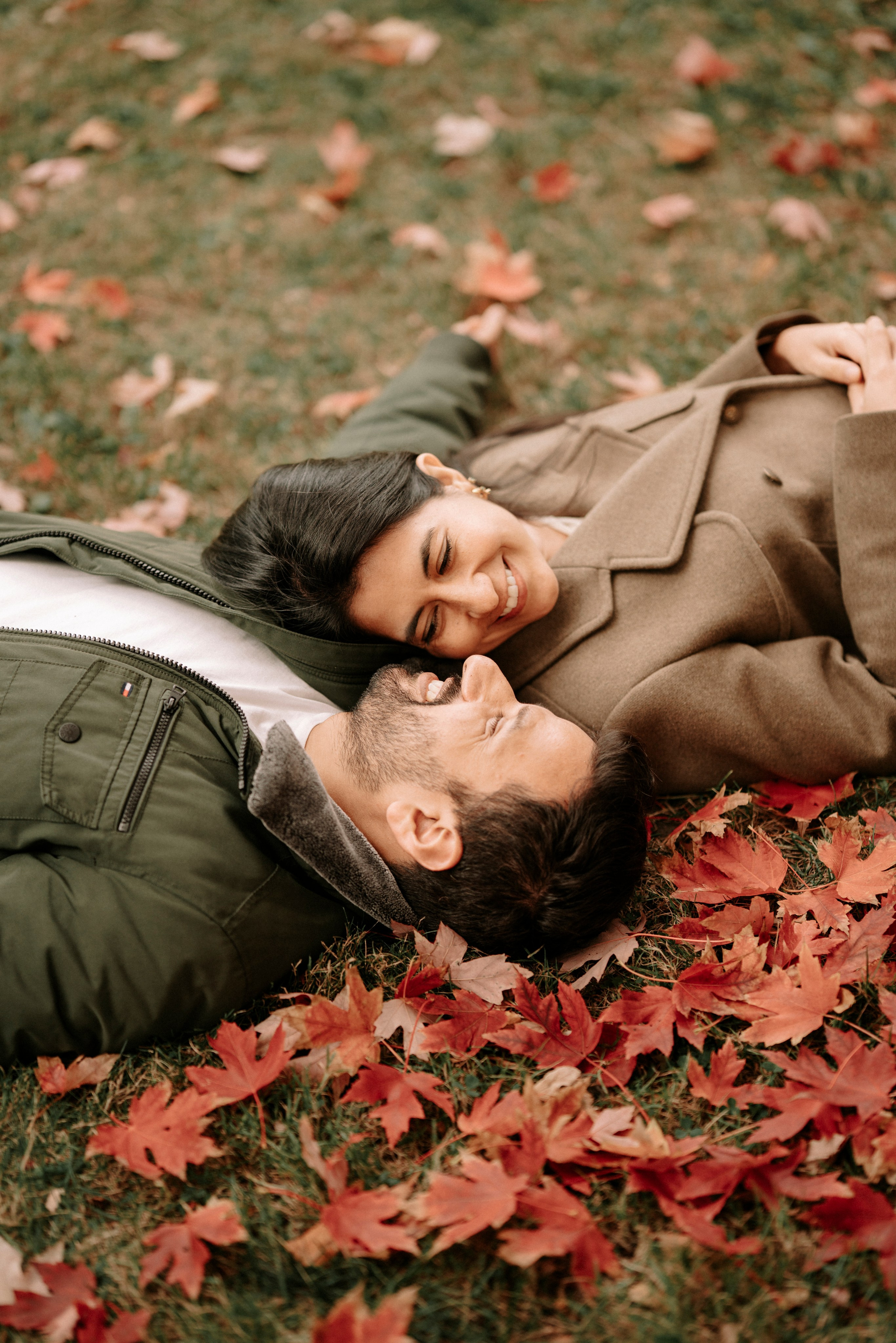 Bride and groom laying on ground with maple leafs