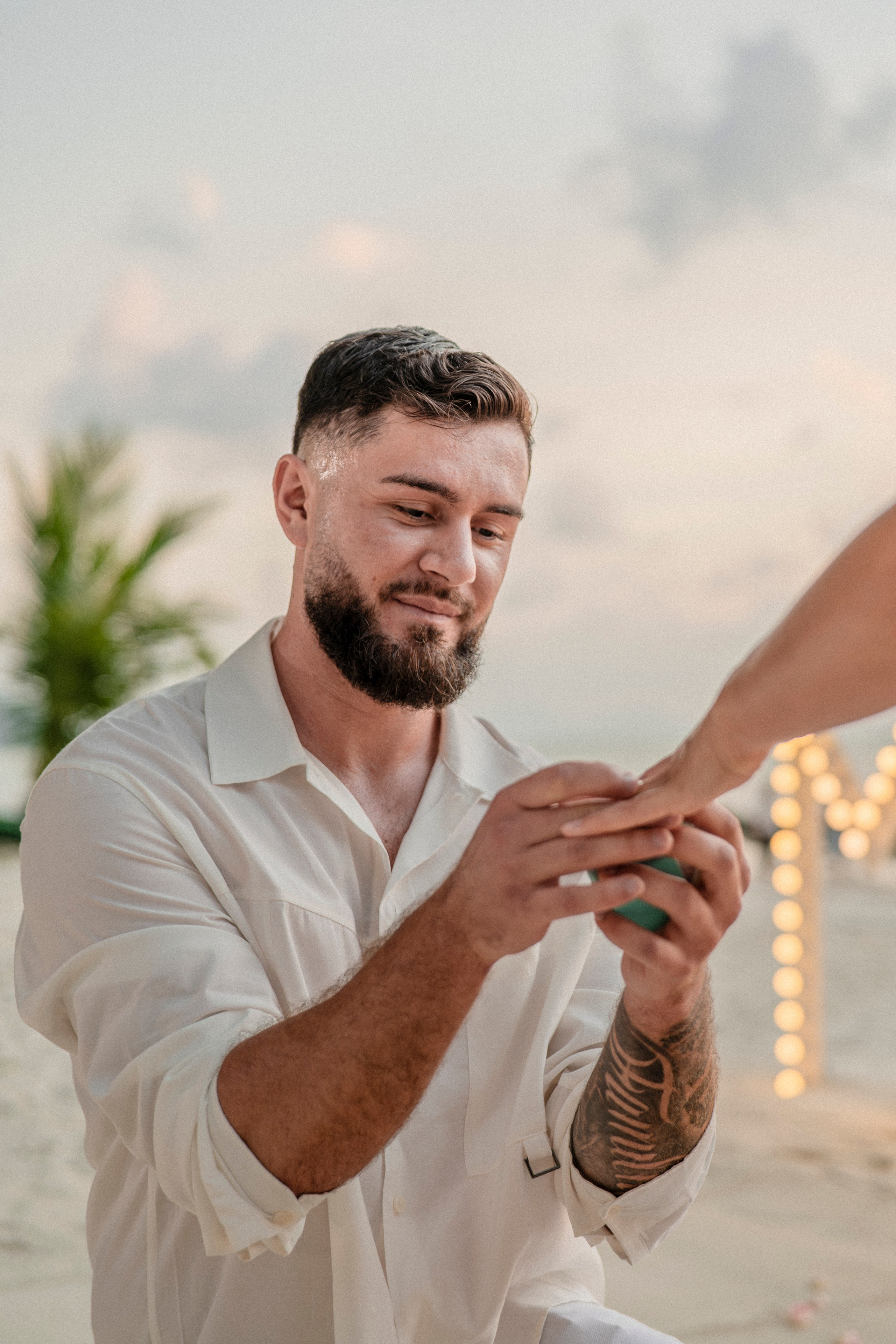 Man gently placing an engagement ring on his partner’s finger during a beach proposal in Pattaya.